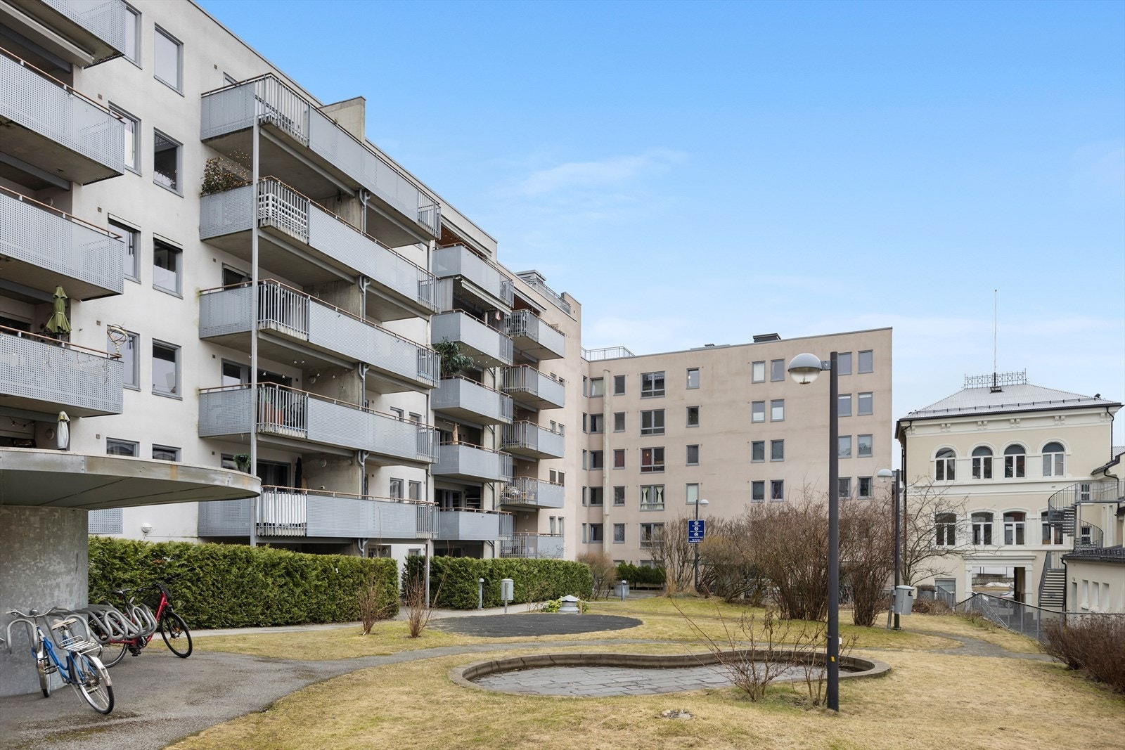 Pene utearealer med belysning, plen, beplantning og sykkelpakering Galleribilde