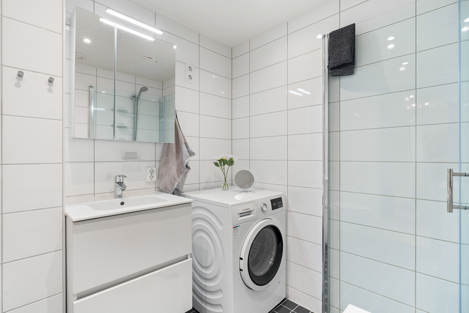 Videre er det opplegg for vaskemaskin, samt montert veggmonter toalett, dusjhjørne med svingdører, håndholdt dusj og termostatstyrt blandebatteri. Galleribilde