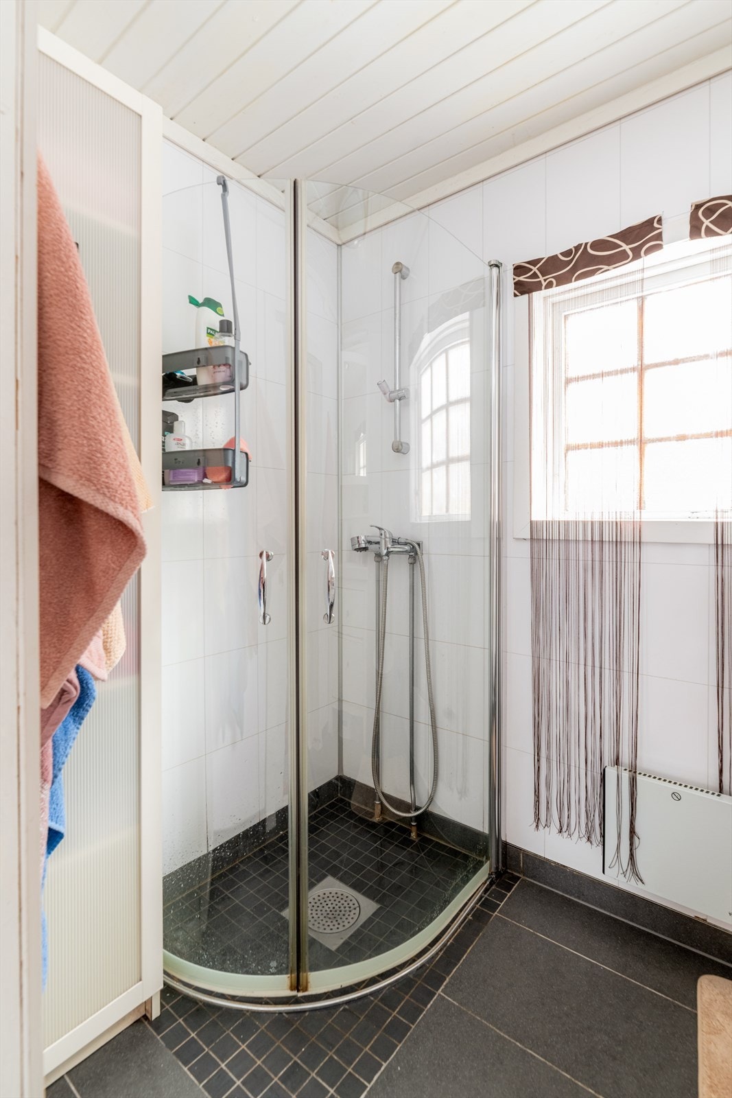 Badet har en enkel innredning med servant, dusjhjørne med dusjvegger og toalett. Malt trepanel i taket er av eldre dato. Dør inn til rommet er original skyvedør. Vindu benyttes for utlufting av rommet. Galleribilde