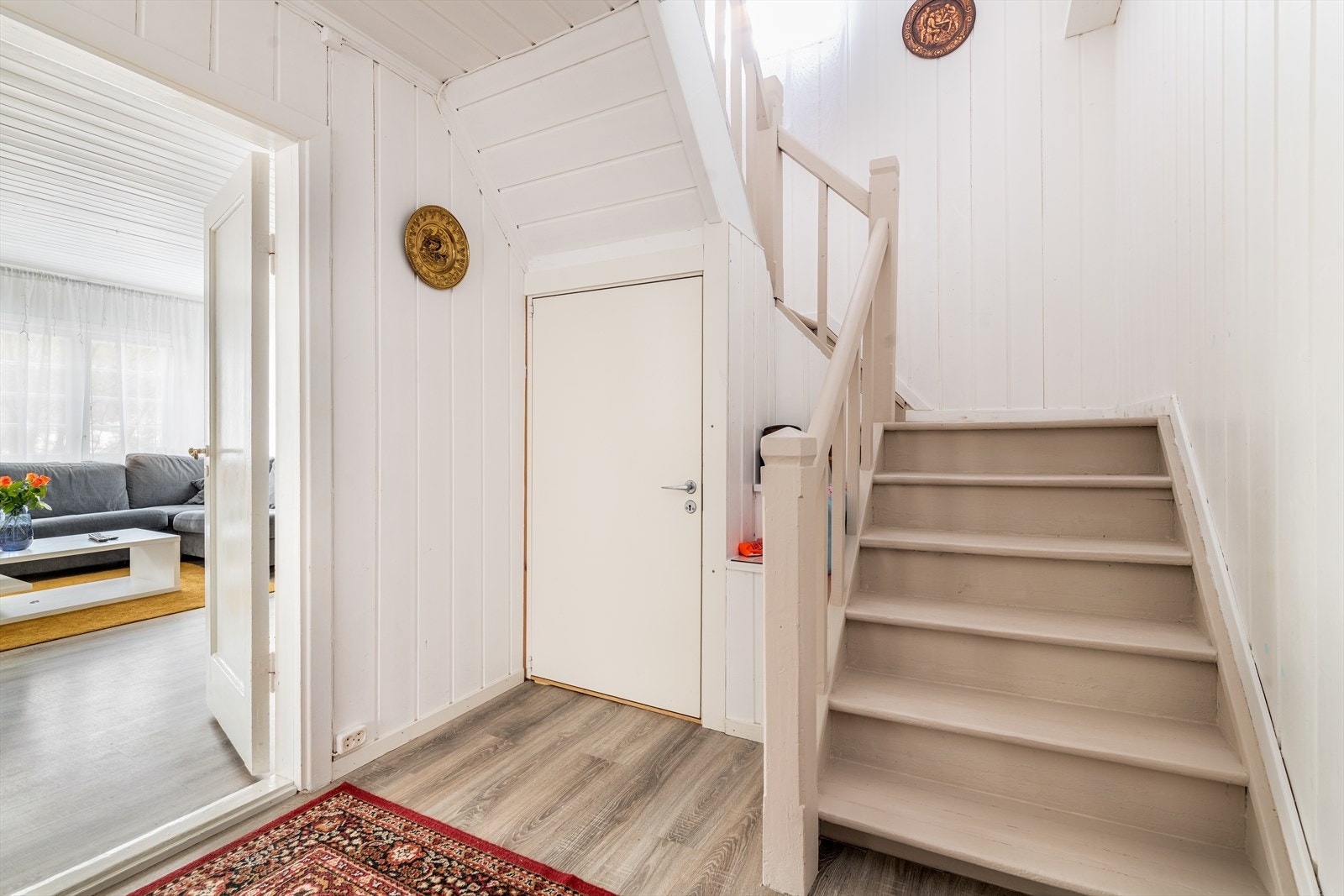 Her er det en moderne laminat på gulvet som går videre inn i etasjen og binder rommene fint sammen. Lukket tretrapp opp til 2. etasje, og dør med adkomst ned til kjeller. Galleribilde