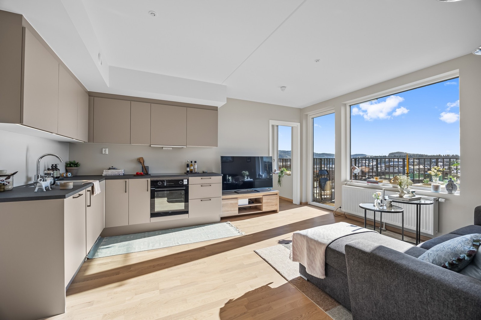 Stuen har eikeparkett og beige vegger, og den åpne løsningen mot kjøkkenet gir en sosial og innbydende atmosfære - perfekt for å varte opp gjester. Galleribilde