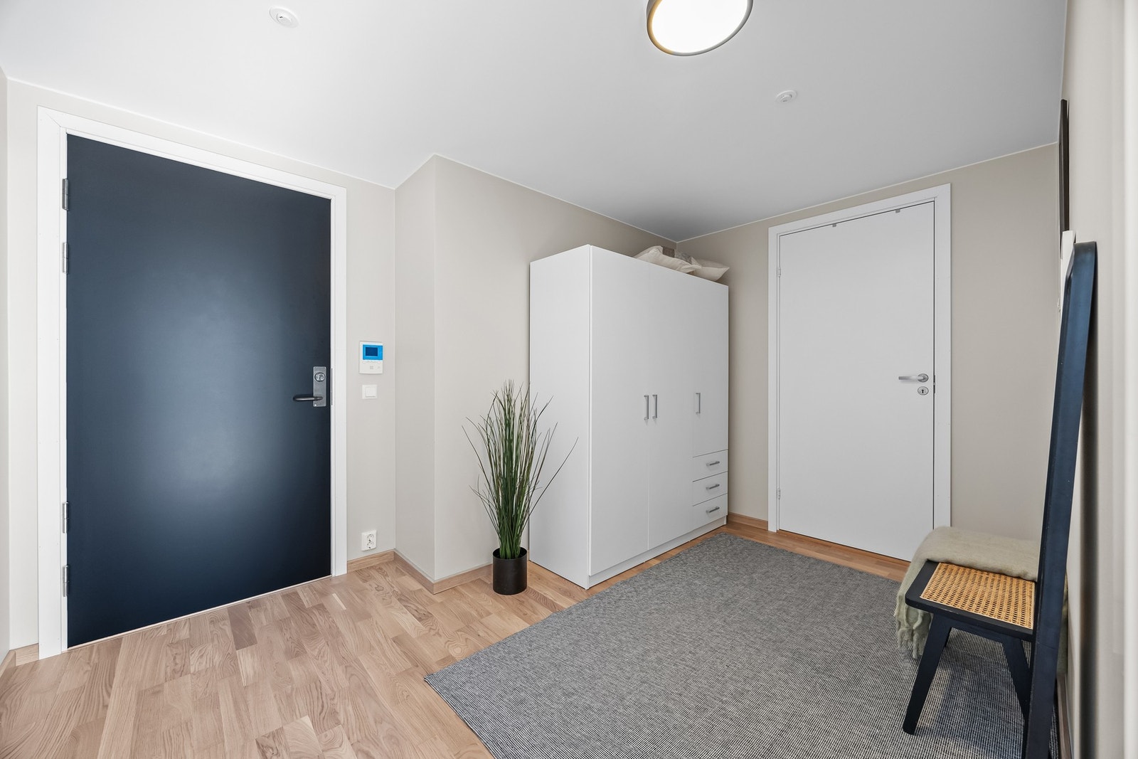 Velkommen inn til en romslig og lys entré med parkettgulv og beige vegger. Galleribilde