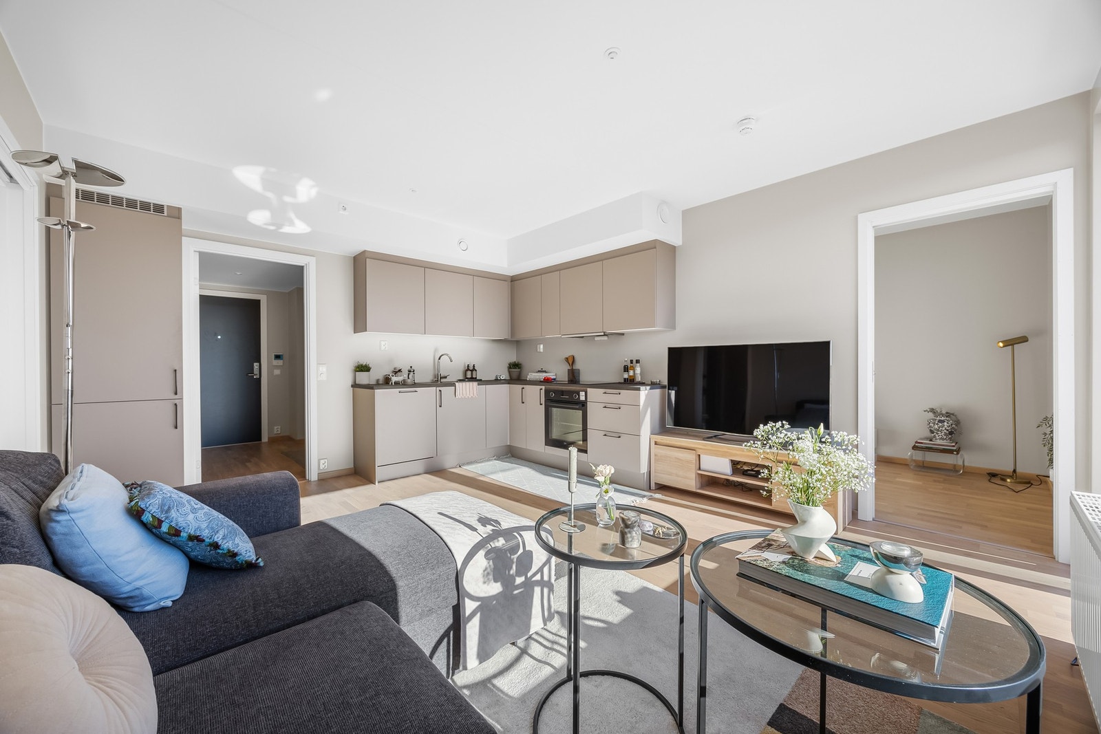 Den beige kjøkkeninnredningen gir et rolig og moderne preg på rommet, og den åpne løsningen gjør det enkelt å lage mat mens du er i selskap med gjestene i stuen. Galleribilde