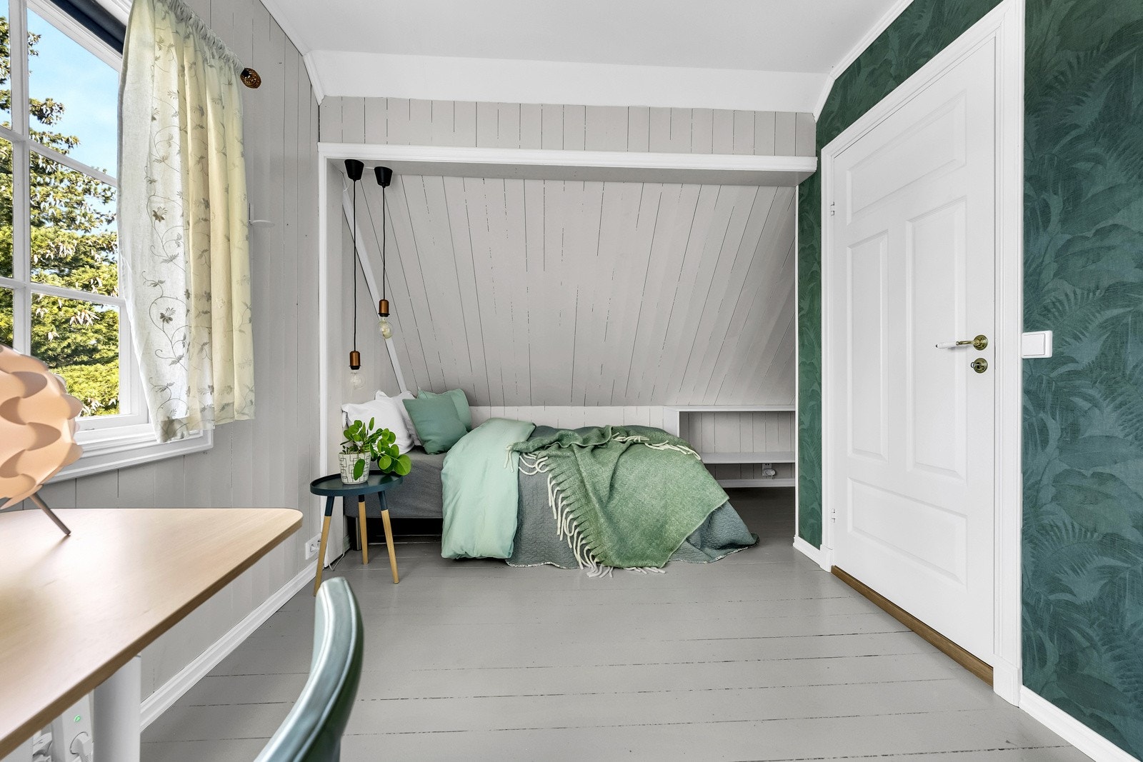 Soverom 2 ligger i andre etasje og har gråmalte gulv og vegger med en kontrastvegg med blå-grønn tapet. Galleribilde