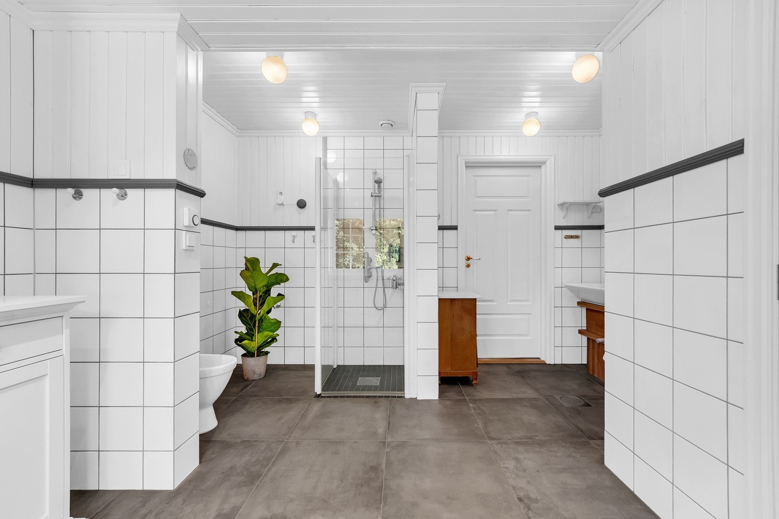Bad nr. 1 ligger i første etasje og har store delikate fliser på gulv og klassiske hvite på veggene. Øvre del av veggen er malt panel med en gråmalt list som skaper en fin kontrast. Galleribilde