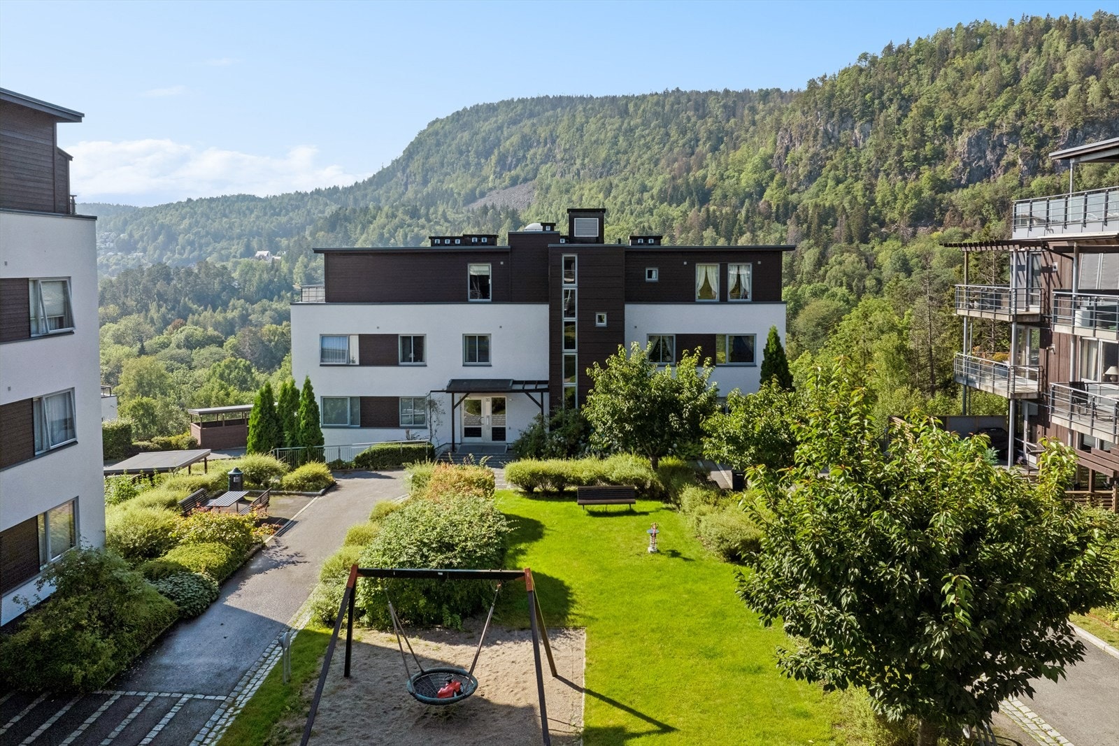 Fellesområdet er pent opparbeidet med asfalterte gangveier, gressplen, beplantning, trær og lekeplass. Galleribilde