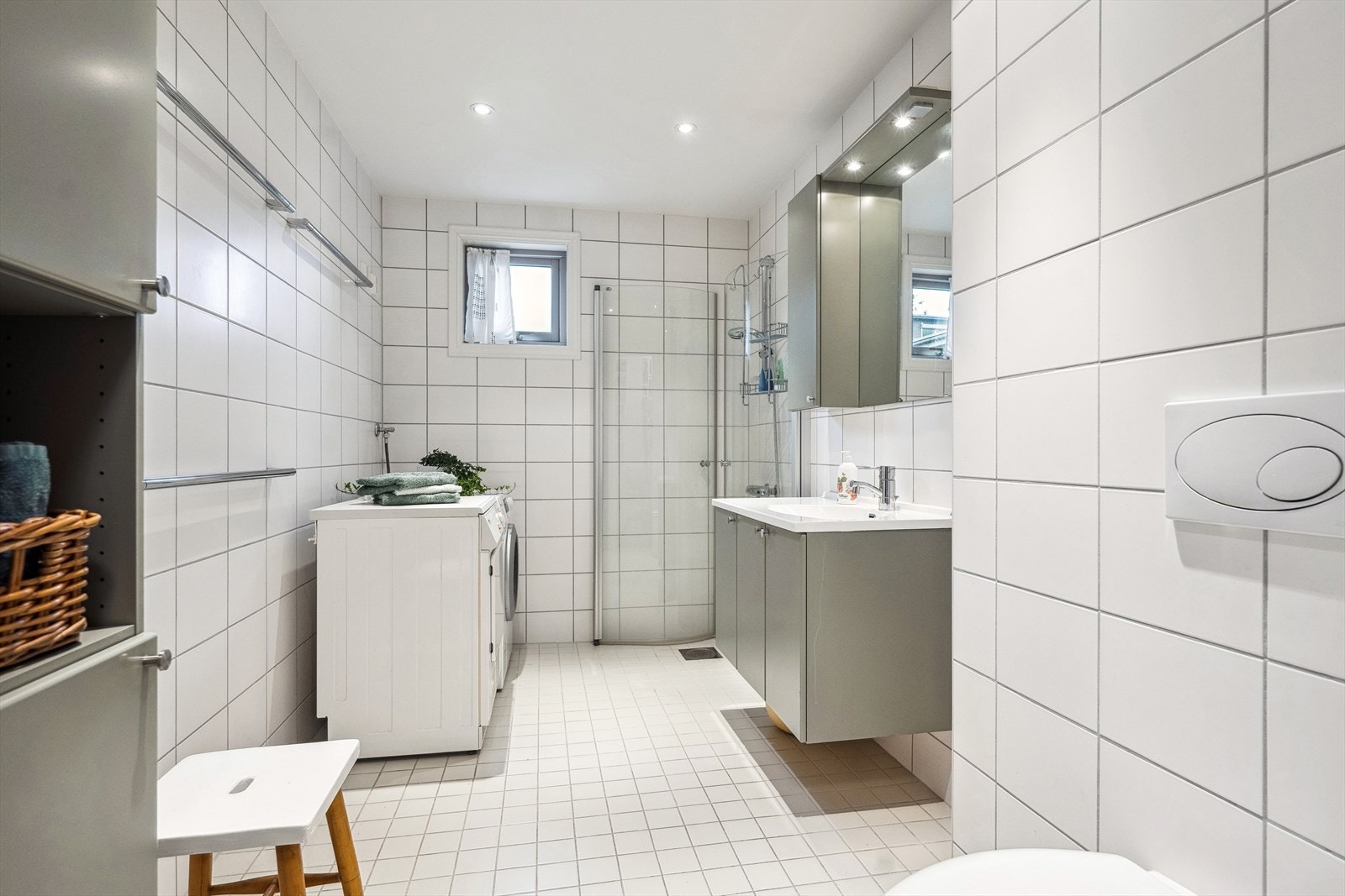 Dette baderommet er innredet med et veggmontert toalett, en enkel servant, og opplegg for vaskemaskin. Galleribilde