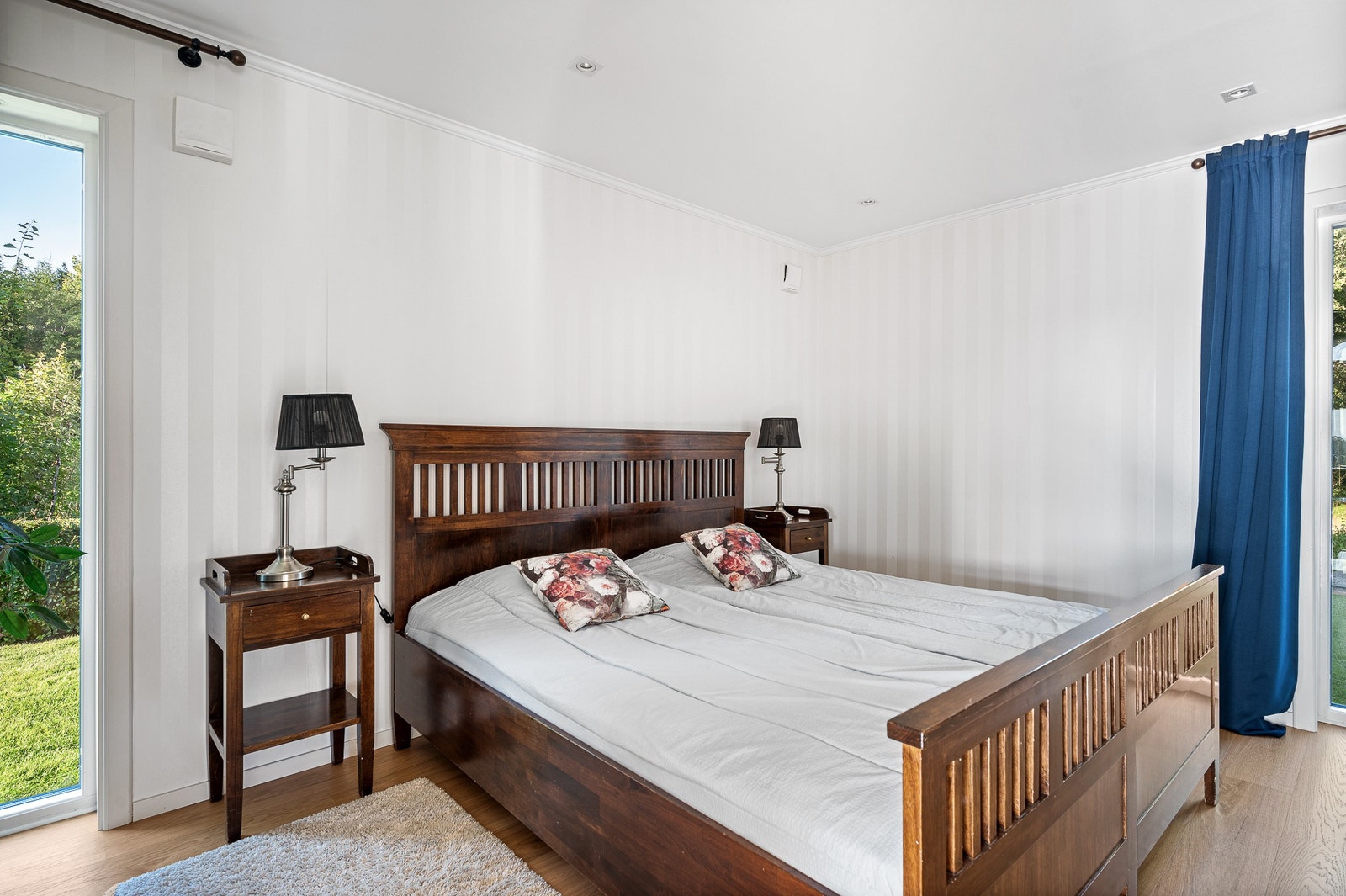 Större sovrum 1 i ljus stil, fönster går från golv till tak vilket verkligen bidrar till att bjuda in ljuset och naturen där ute. Galleribilde