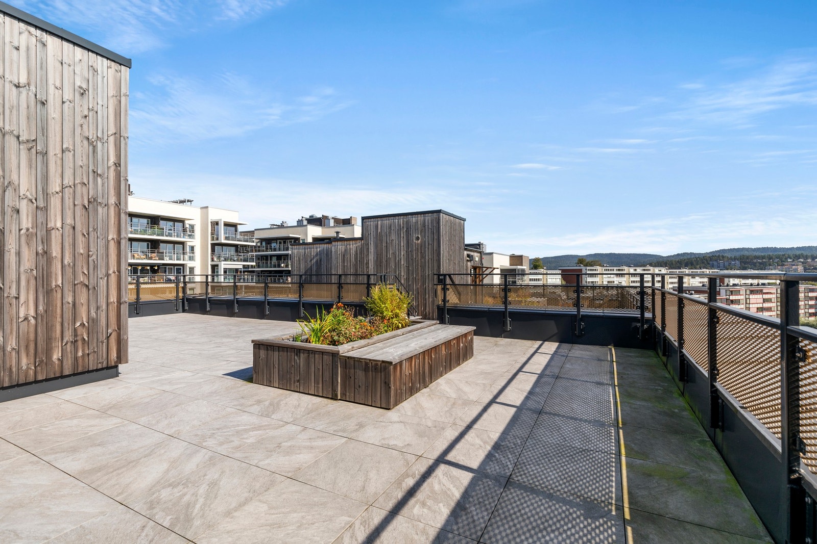 Nyt lange sommerkvelder på en flott takterrasse med grønne innslag og utsyn over nærområdet. Galleribilde