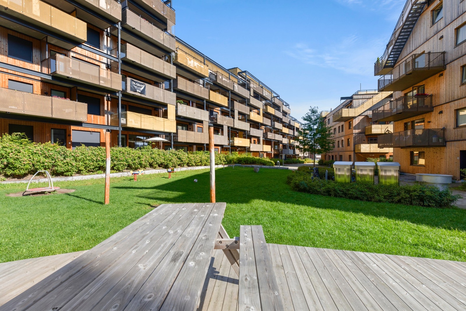 Et flott opparbeidet fellesområde med sittegrupper, lekeplass og grønne omgivelser. Galleribilde