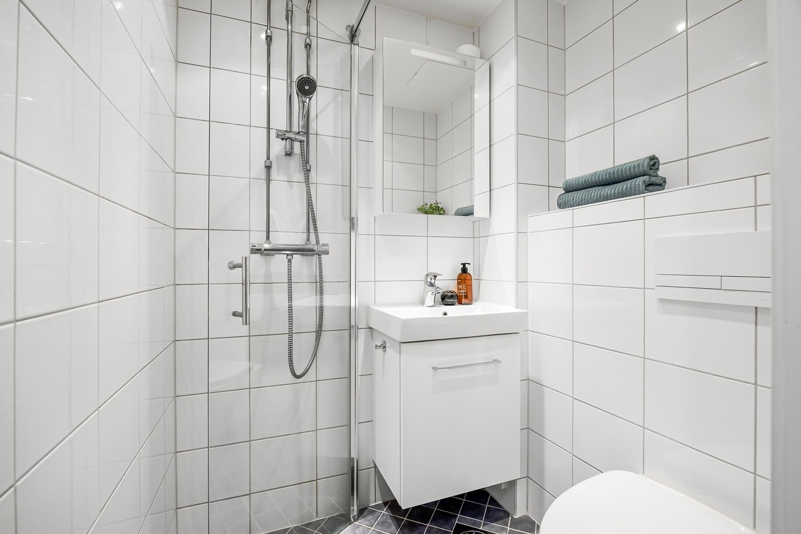 Inneholder vegghengt WC, dusjplass med inn- og utadslående glassvegger, servant med ettgreps blandebatteri i innredning og opplegg for vaskemaskin. Galleribilde