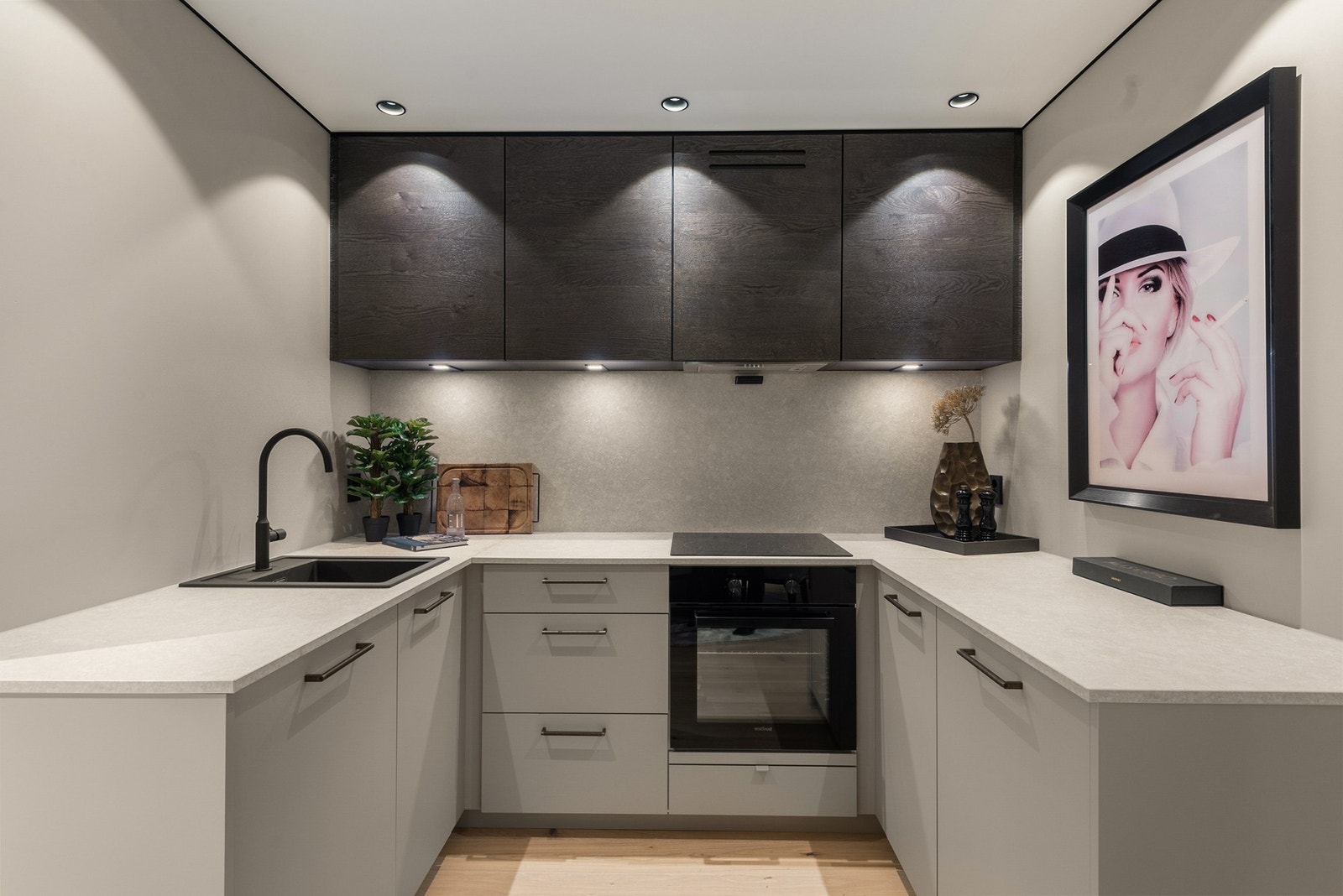 Innredningen er toppmoderne, med glatte, lysegrå fronter, mørke overskap, lekre, dimbare lys-detaljer og sort oppvaskkum nedfelt i en grå benkeplate av laminat. Galleribilde