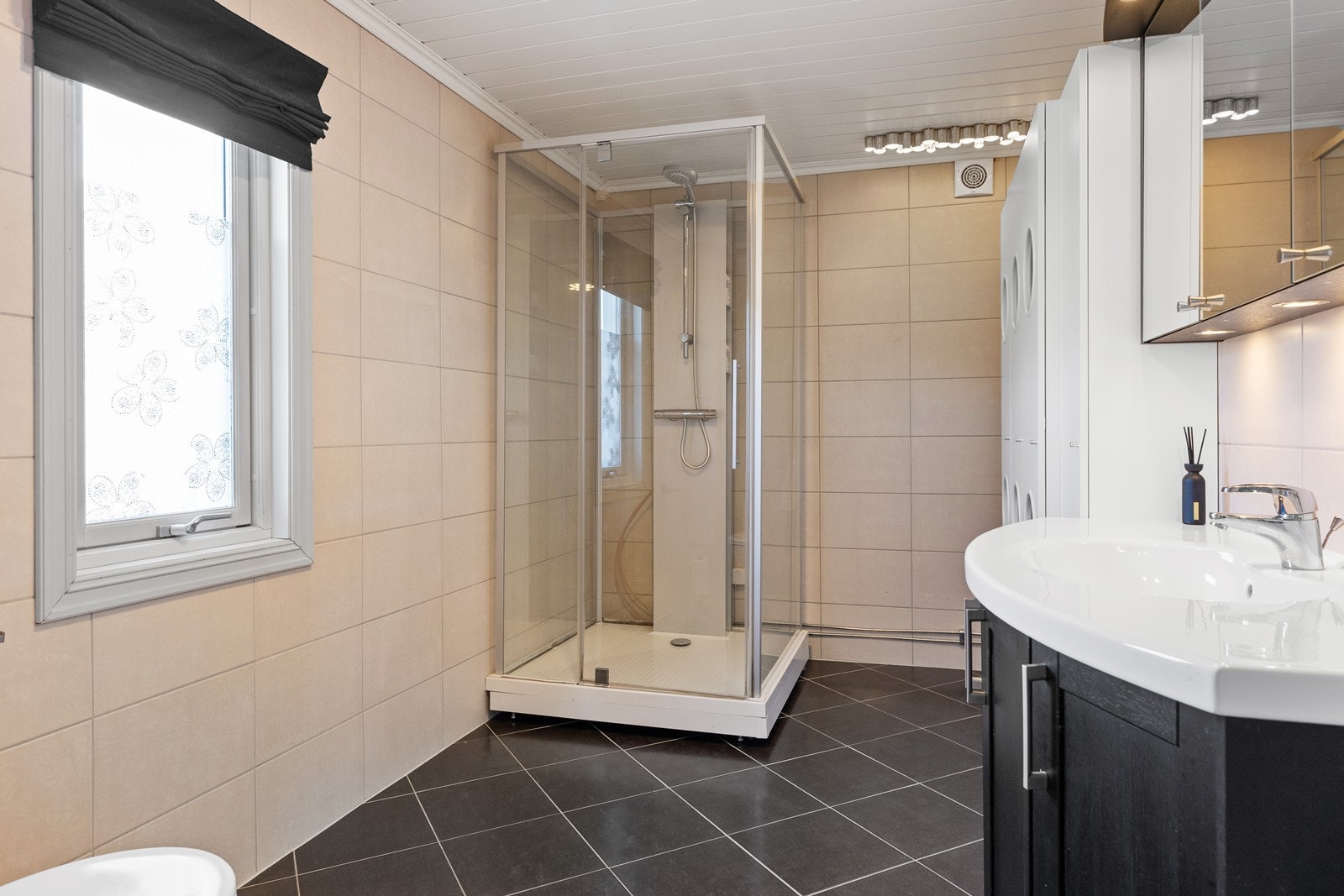 Romslig baderom med gulvvarme, gulvmontert klosett, servantinnredning og dusjkabinett. Galleribilde