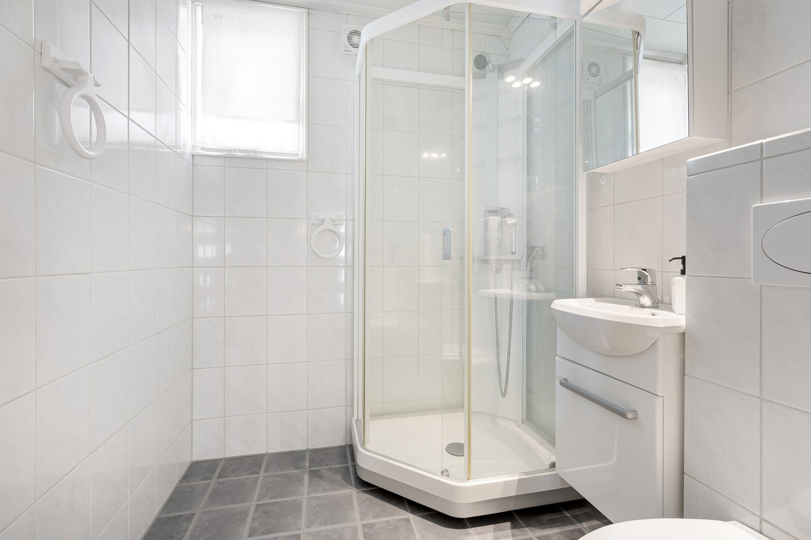 Bad i underetasjen er innredet med dusjkabinett, innredning med servant, speil og belysning. Vegghengt wc med innebygget sisterne. Galleribilde