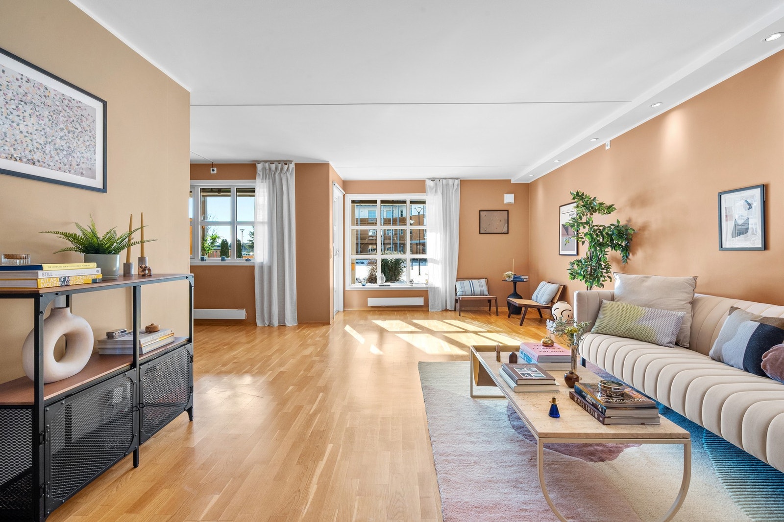 Med varme fargetoner på veggene, parkett på gulvet og spotter i taket skapes en innbydende atmosfære. De store vinduene slipper inn rikelig med dagslys og gir rommet en luftig følelse. Galleribilde