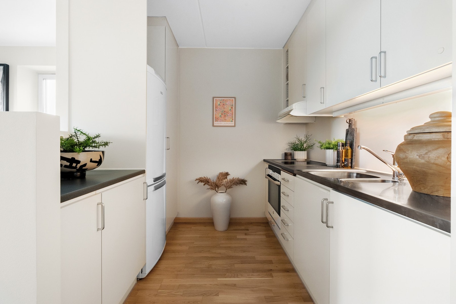 Kjøkkeninnredning med glatte fronter, laminat benkeplate, lys under overskap m.m. Galleribilde