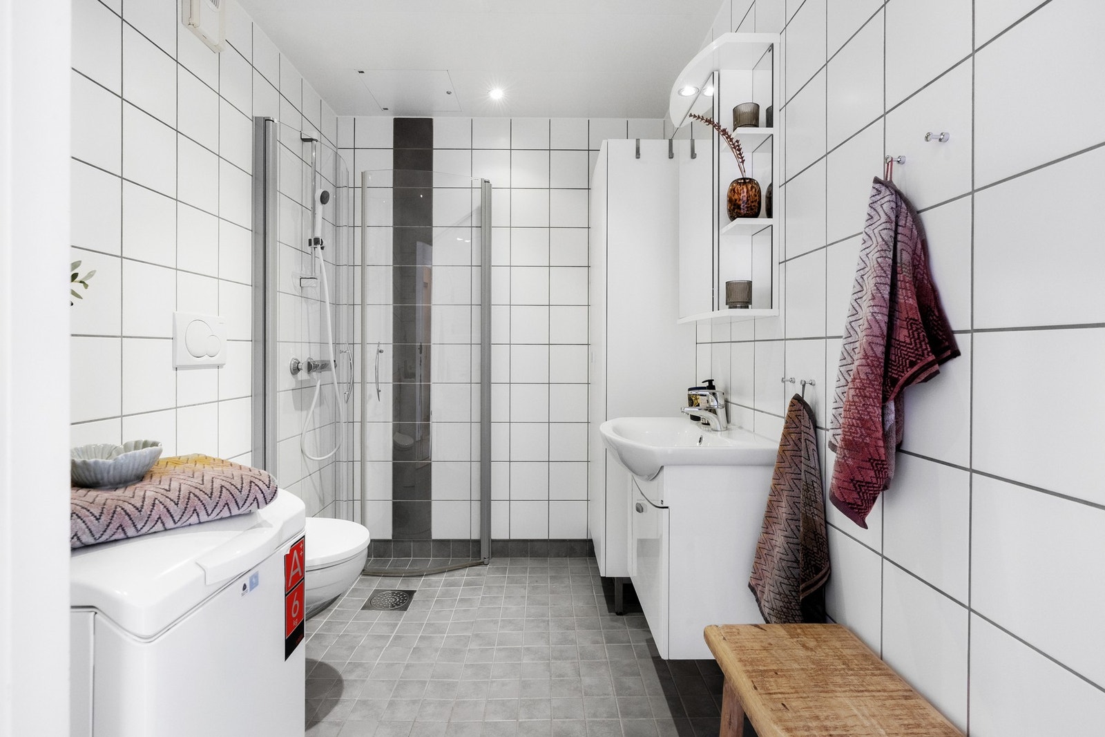 Leiligheten har et pent flislagt baderom av god størrelse. Tidløst flisvalg, opplegg for vaskemaskin/tørketrommel, vegghengt WC og dusjehjørne med svingdører Galleribilde