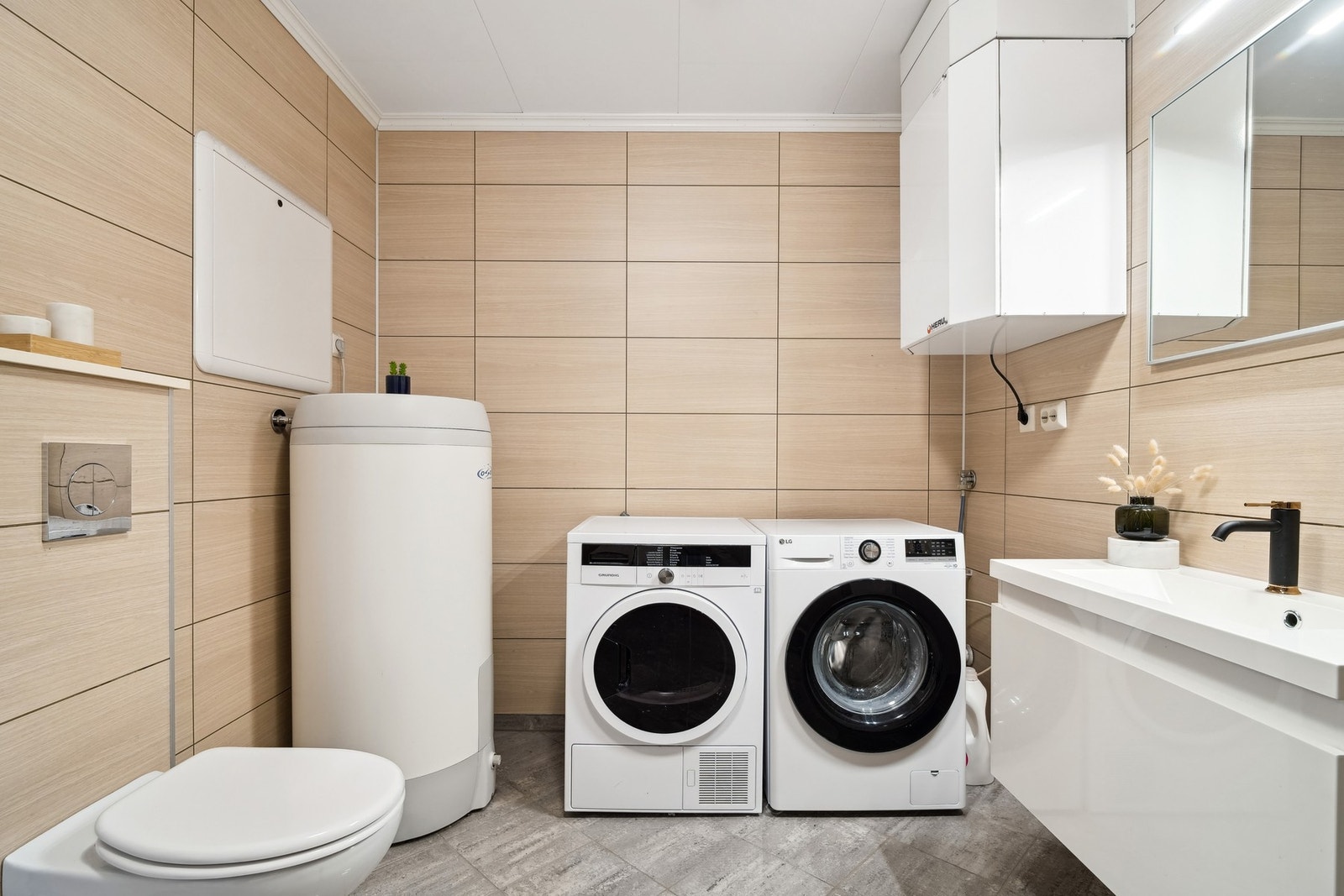 Badet i 1.etasje er kombinert med vaskerom. Baderomsplater på vegger og flislagt gulv med elektriske varmekabler. Galleribilde