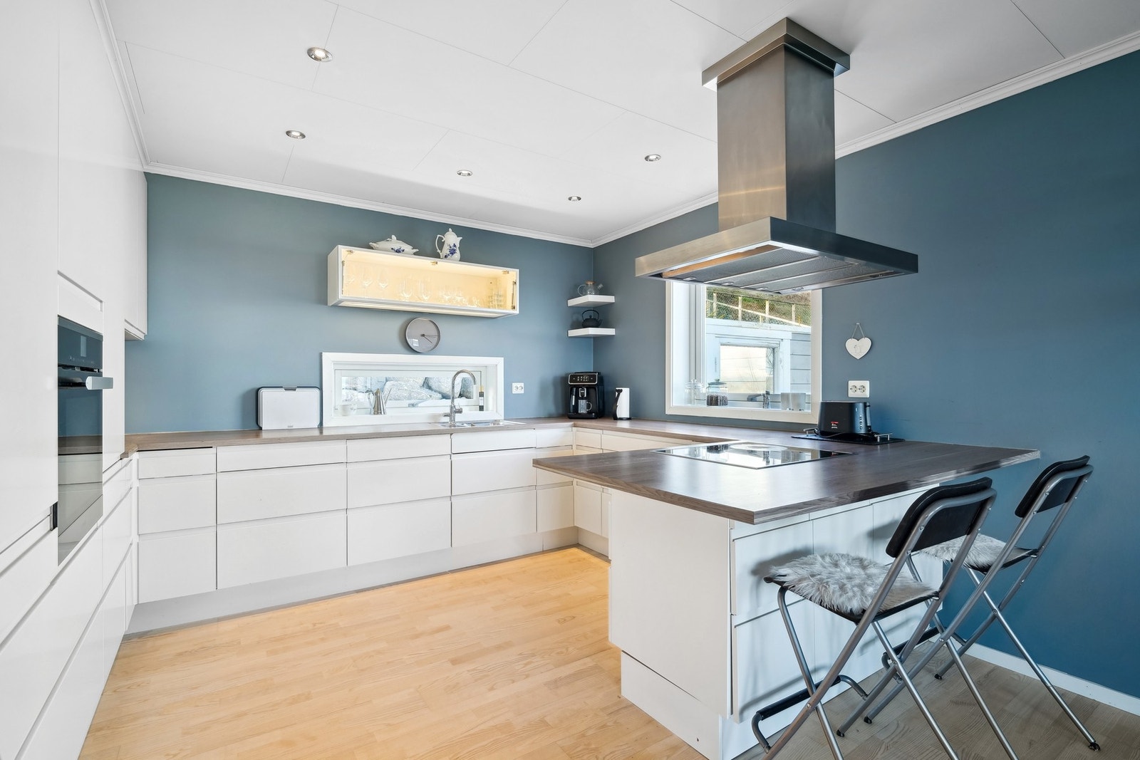 Innredning med hvite takhøye fronter og laminat benkeplate. Effektiv utnyttelse av kjøkkenet er kjøkkenøyen som gir to ekstra spiseplasser. Galleribilde