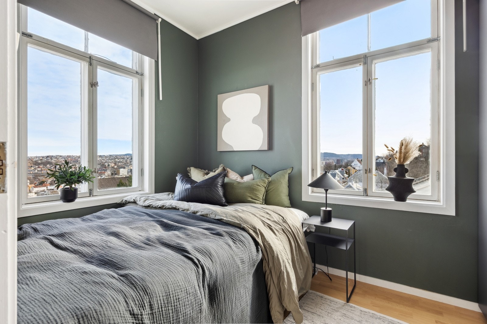 Romslig soverom malt i moderne farger med store vindusflater som gir rikelig med naturlig lys. Rommet er stilfullt innredet med en praktisk skyvedørsgarderobe fra 2024. Galleribilde