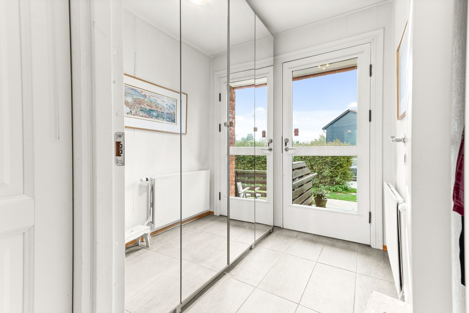 Entré med flislagt gulv og garderobeskap med speil. Galleribilde