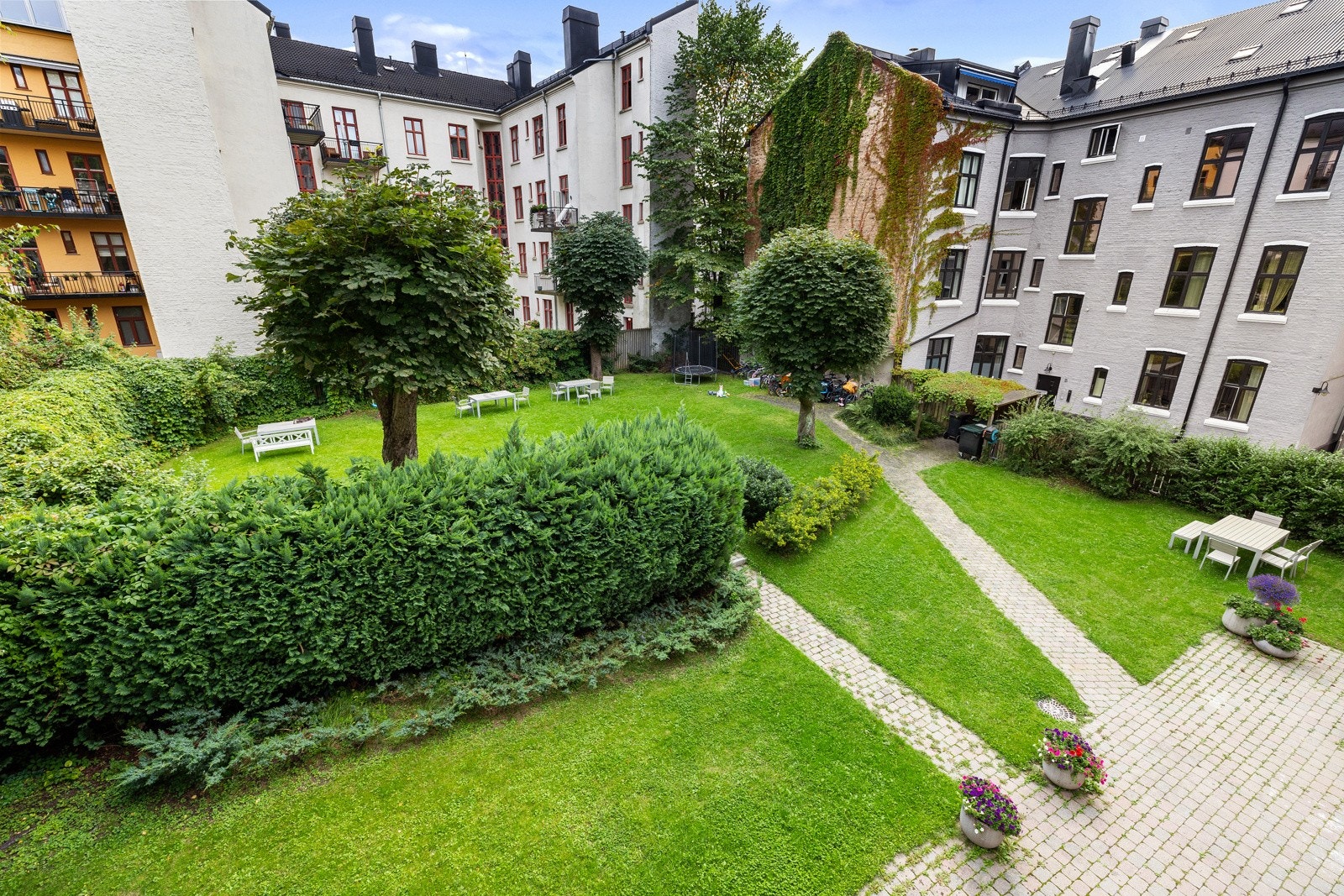 Fra balkongen har du utsikt mot en frodig og innbydende bakgård med en hyggelig sittegruppe, perfekt for rolige stunder utendørs. Galleribilde