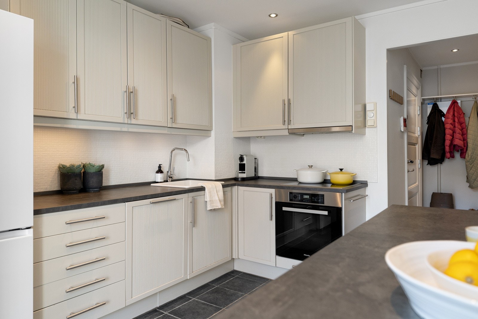 Den nedsenkede kummen i keramikk, integrerte hvitevarer og flislagt vegg over benken skaper et stilrent og funksjonelt uttrykk. Galleribilde