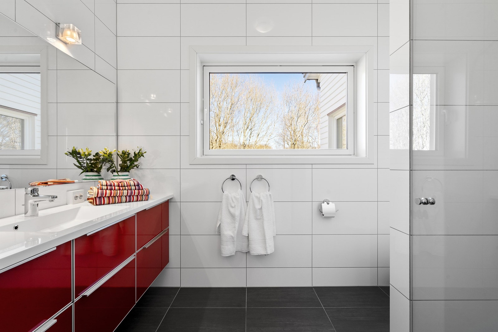 Flott helfliset bad III med dusjnisje, vegghengt toalett, servant med skuffer og stort speil på vegg. Det er varme i gulv og spotter i tak. Baderomsinnredningen er fra HTH. Det er sto vindu på badet som gir godt med naturlig lys. Galleribilde
