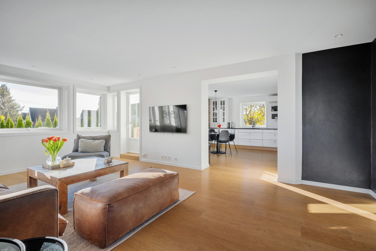 Et pent 1-stavs laminatgulv bidrar til en flytende overgang mellom stuen og kjøkkenet. Galleribilde