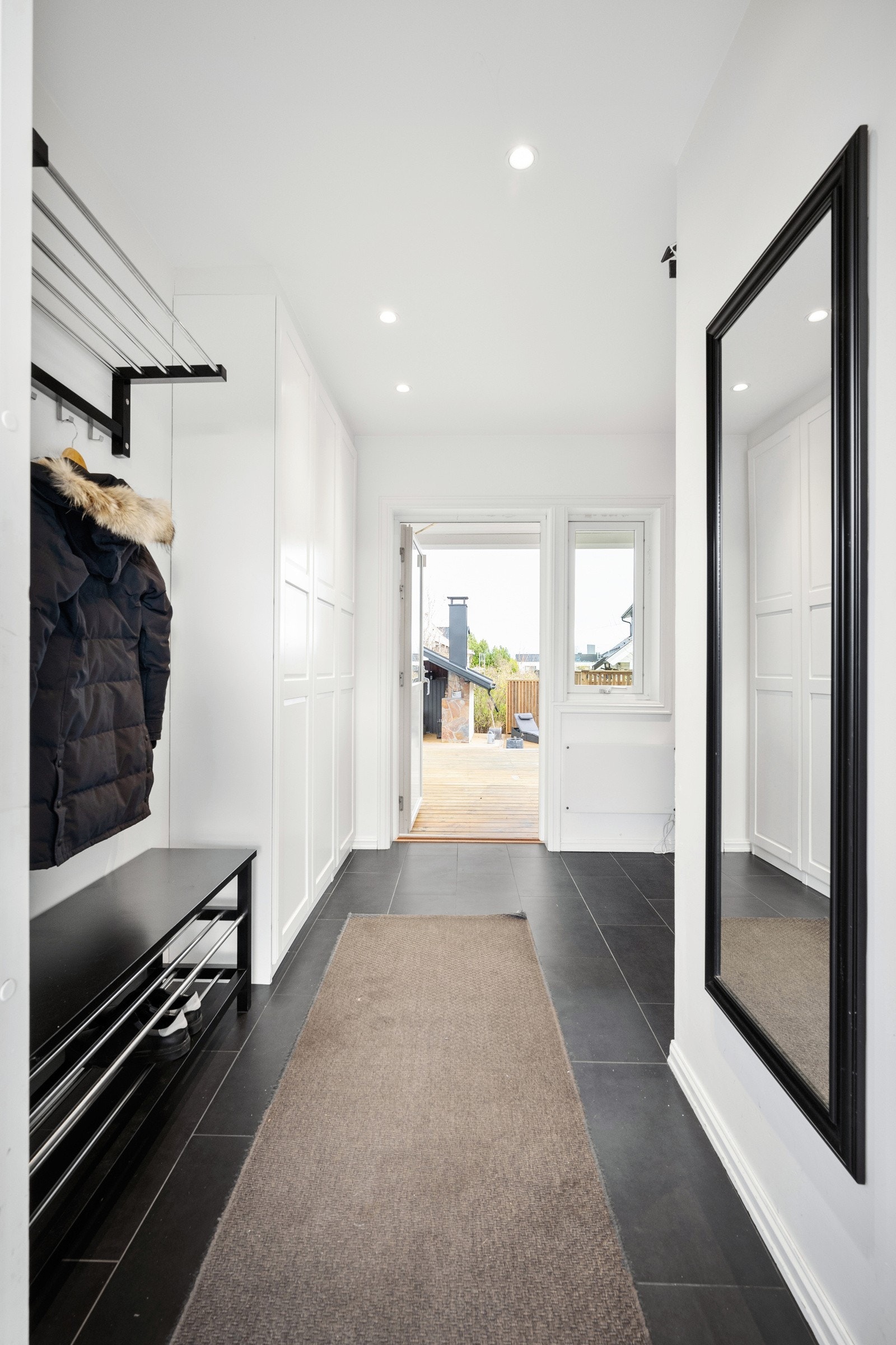 Man ønskes velkommen av en innbydende entré med varmekabler og store, sorte fliser på gulvet. Galleribilde