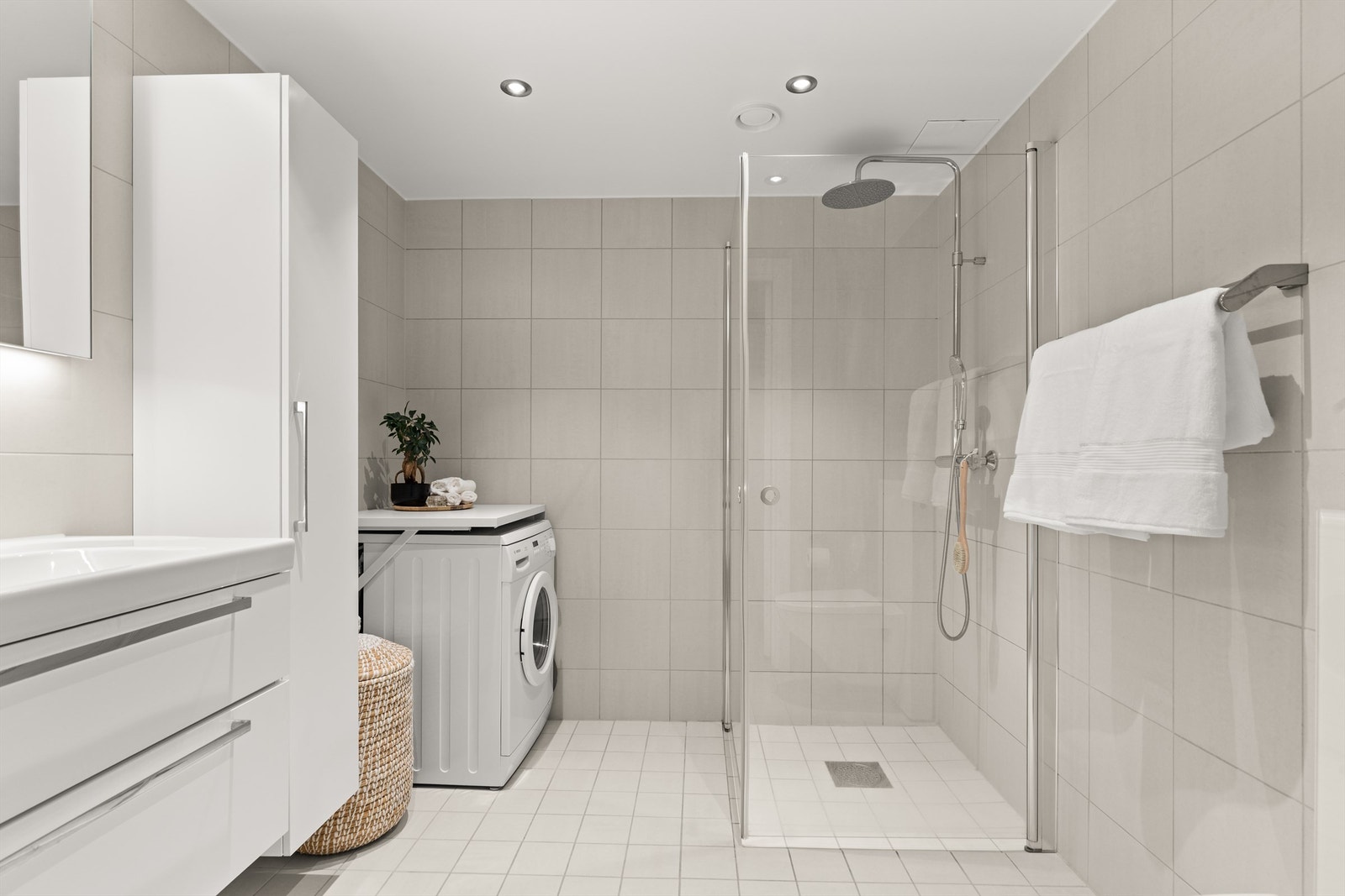 Videre har badet dusjhjørne med regnfallsdusj og glassdører. Her er det også plass og opplegg for vaskemaskin. Galleribilde