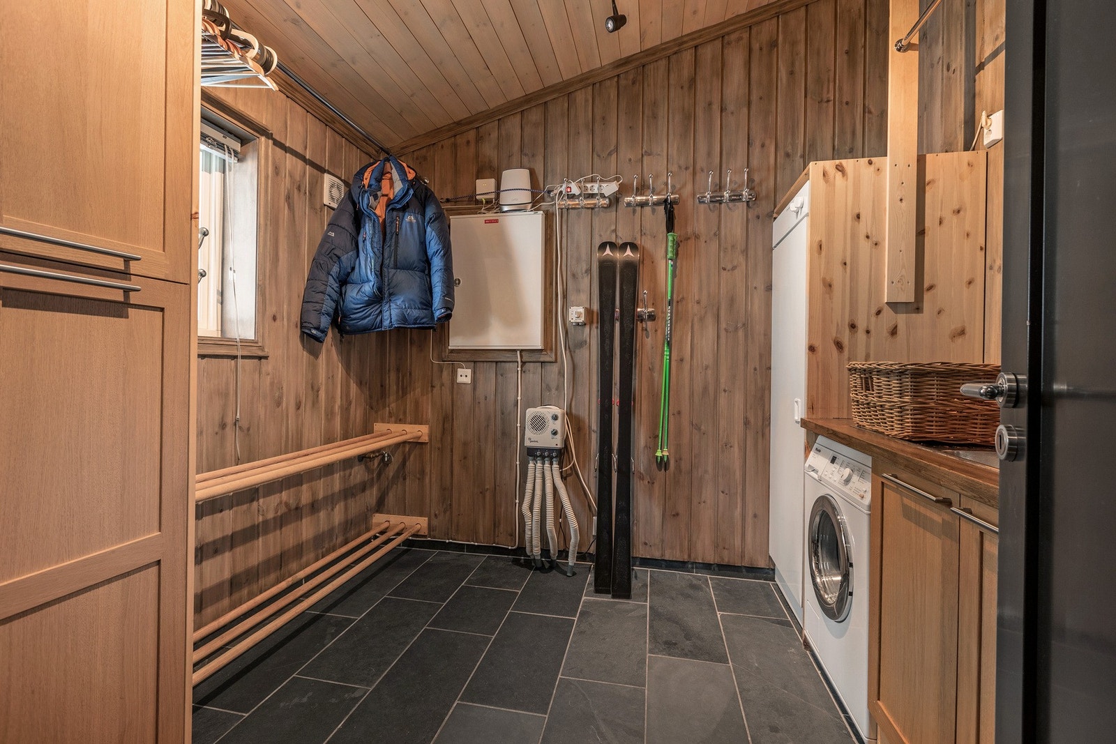 Praktisk vaskerom med flislagt gulv, opplegg for vaskemaskin og godt med skapplass. Galleribilde