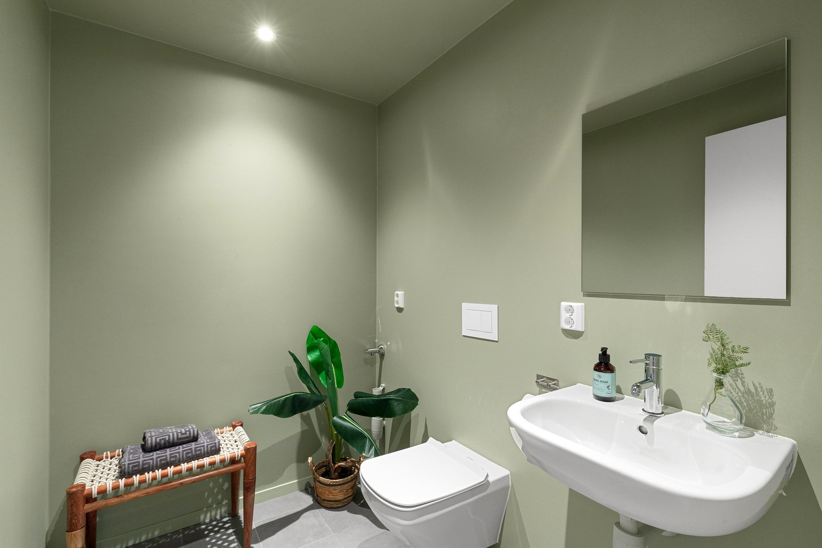 Delikat toalettrom med flislagt gulv, slette vegger og himling malt i en herlig grønnfarge. Downlights i tak. Galleribilde