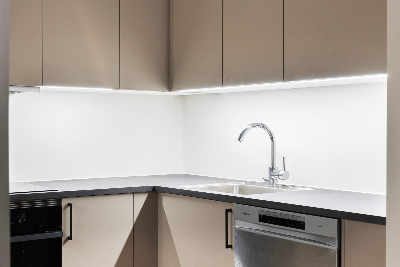 Kjøkkenet har integrerte hvitevarer som komfyr, platetopp, kjøleskap, oppvaskmaskin og ventilator over kokesone. Galleribilde