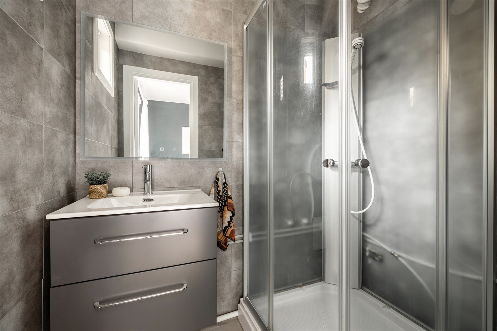 Bad med dusjkabinett og servantskap, samt speil med sminkelys Galleribilde