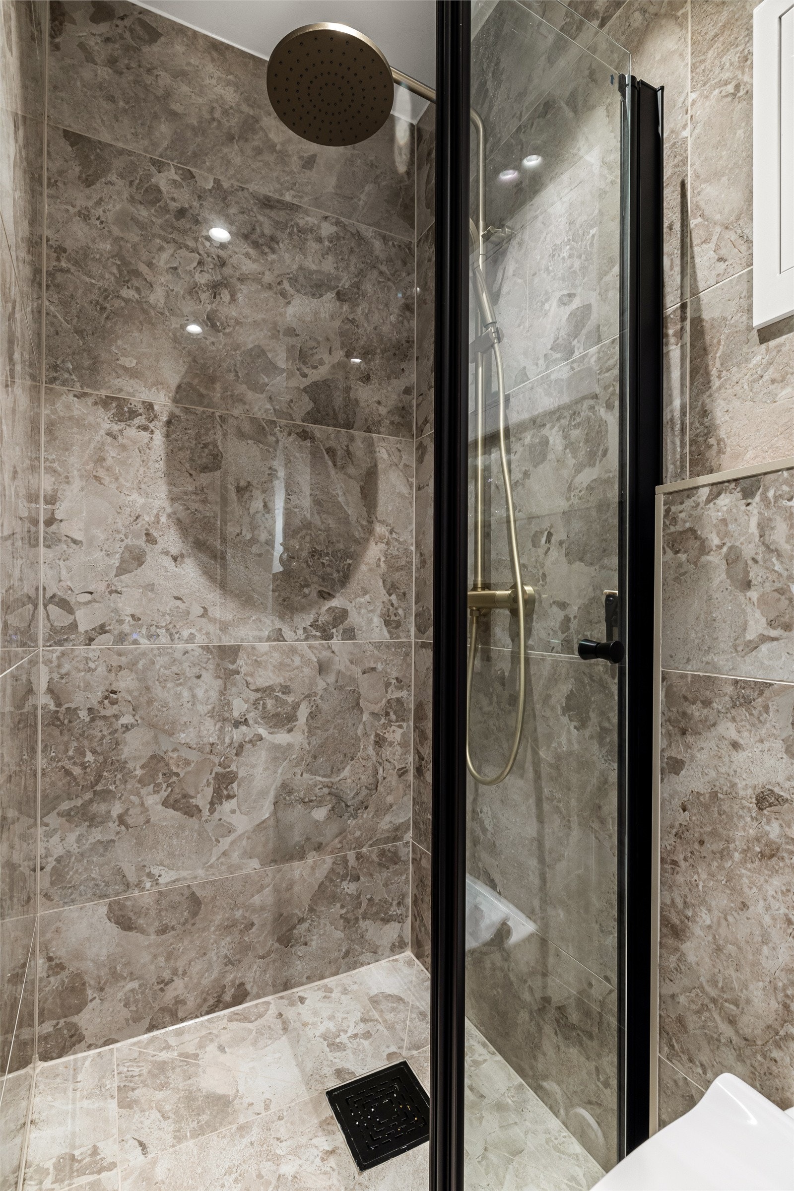 Rommet inneholder en servantseksjon med skuffer, et nedsenket dusjhjørne med inn- og utadslående dører i herdet glass og et praktisk vegghengt toalett. Galleribilde