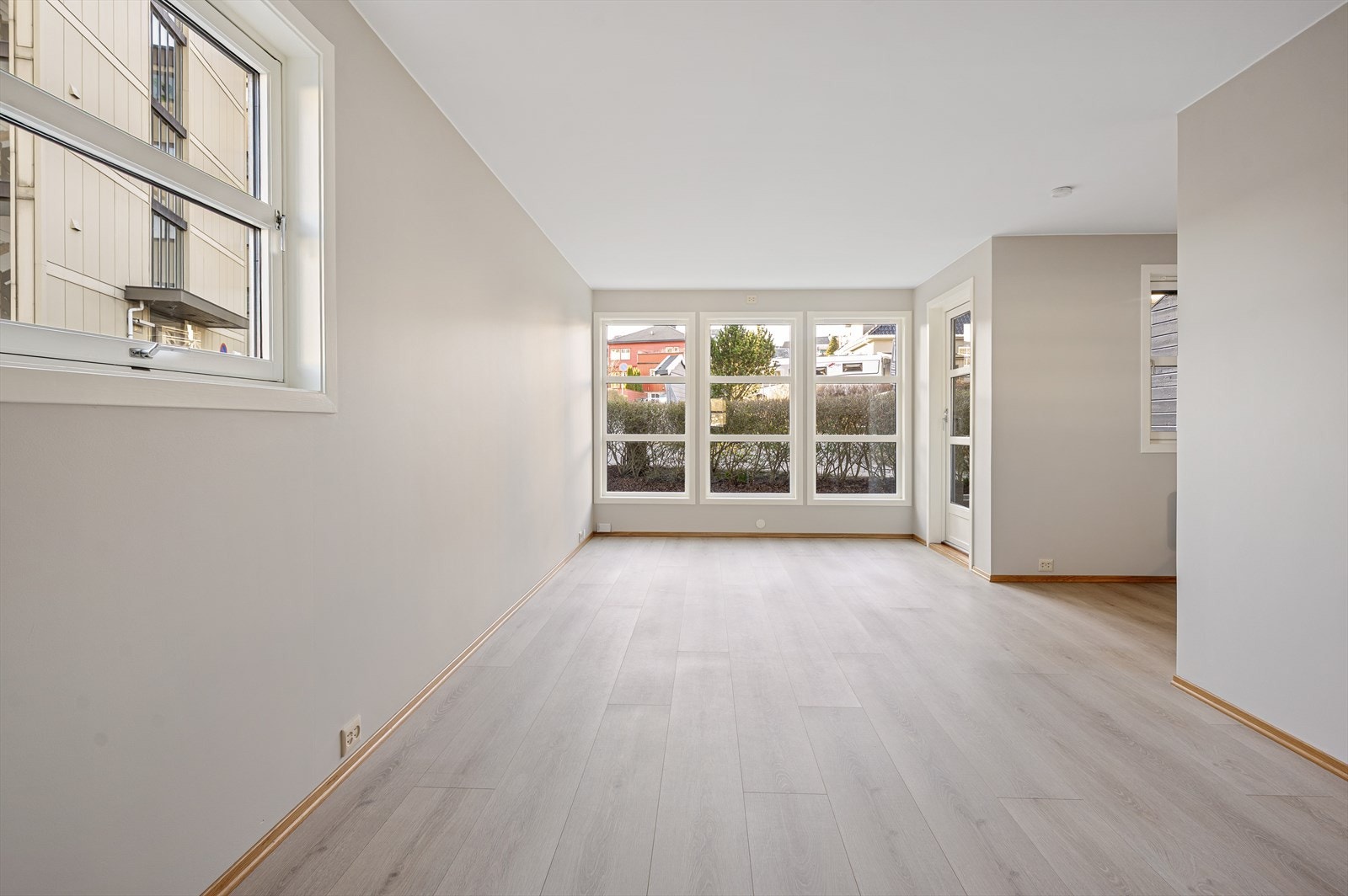 En åpen og lys stue med tidsriktig gulv og harmoniske farger på veggene. Galleribilde