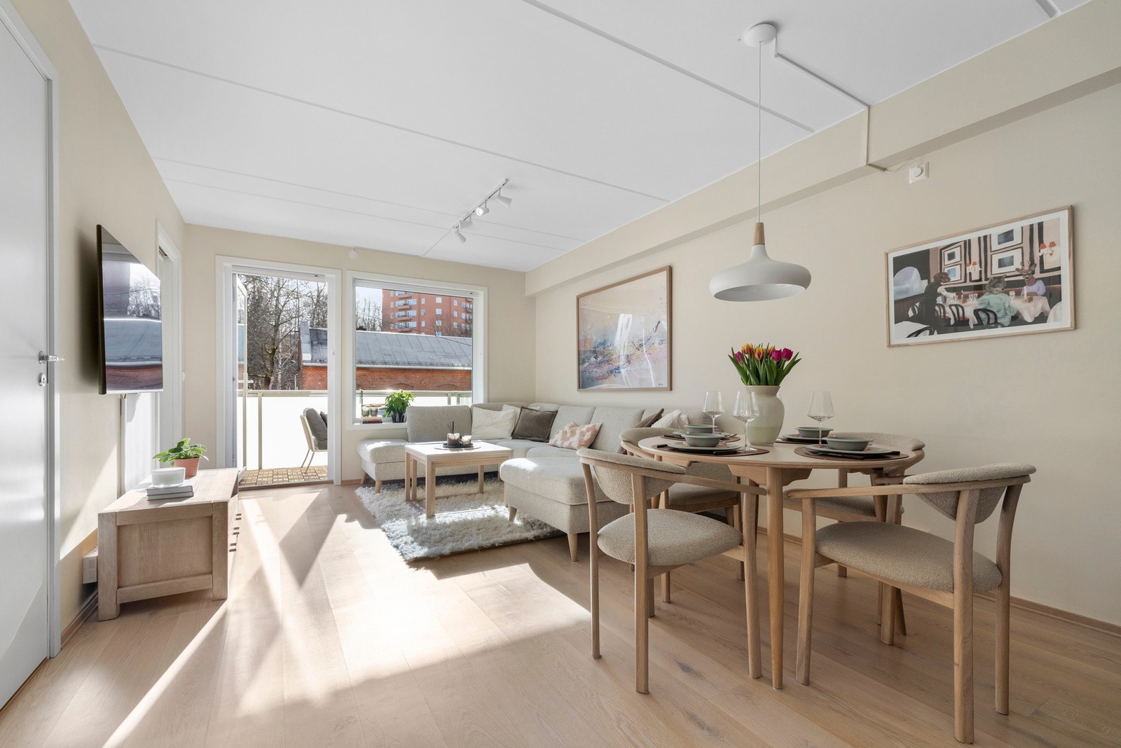 Her befinner vi oss i hjertet av leiligheten, nemlig stuen. Kombinasjonen av de lyse overflatene og rikelig innslipp av naturlig lys skaper en åpen og luftige romfølelse. Galleribilde