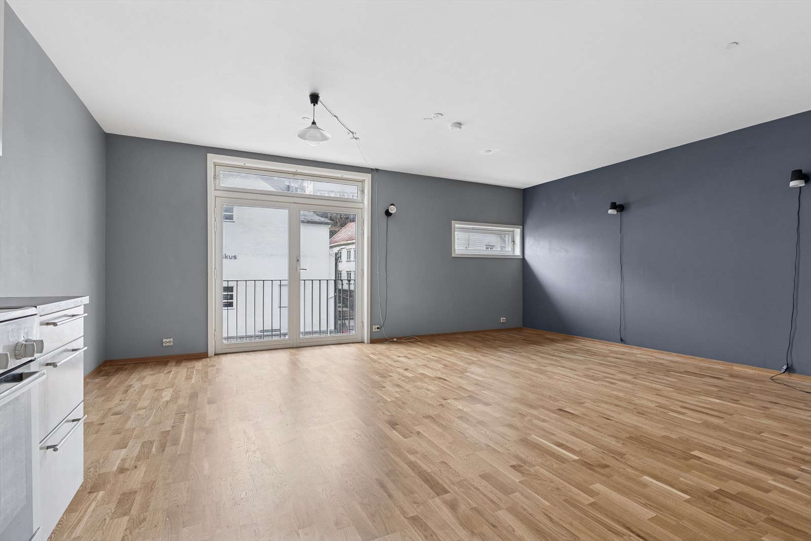 Romslig stue med parkett på gulvet og malte plater på veggene. Galleribilde