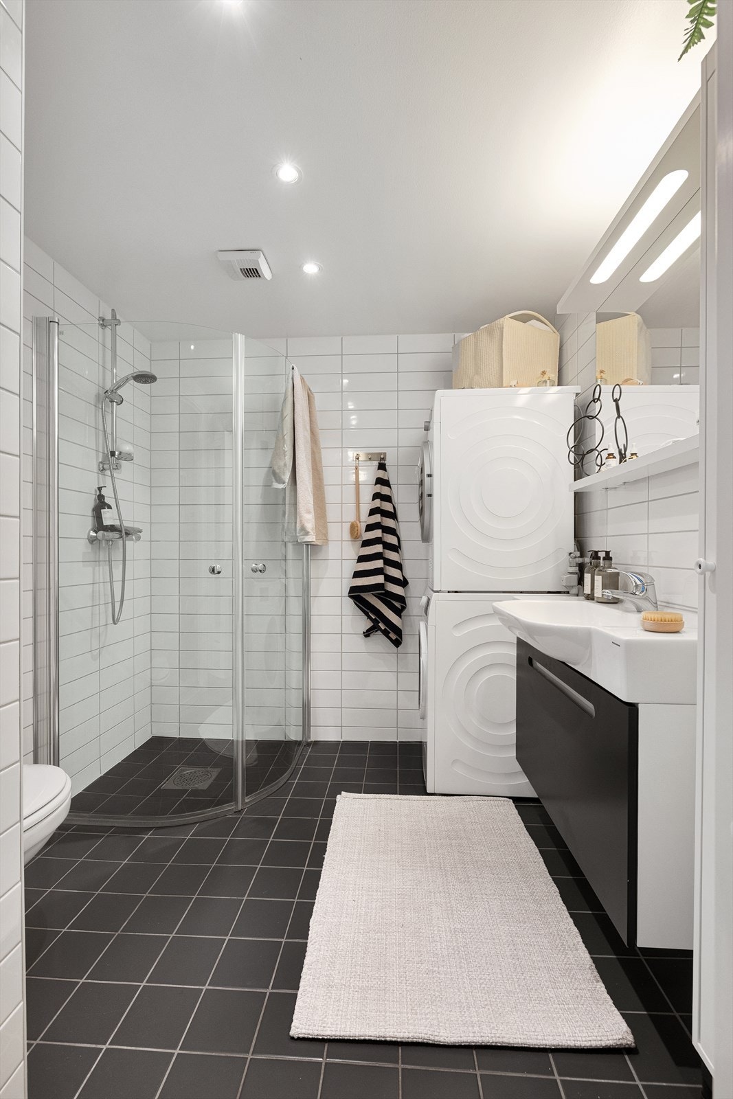 Baderomsinnredningen består av heldekkende servant og underskuff, speil med integrert belysning og et romslig dusjhjørne med buede glassdører. Galleribilde