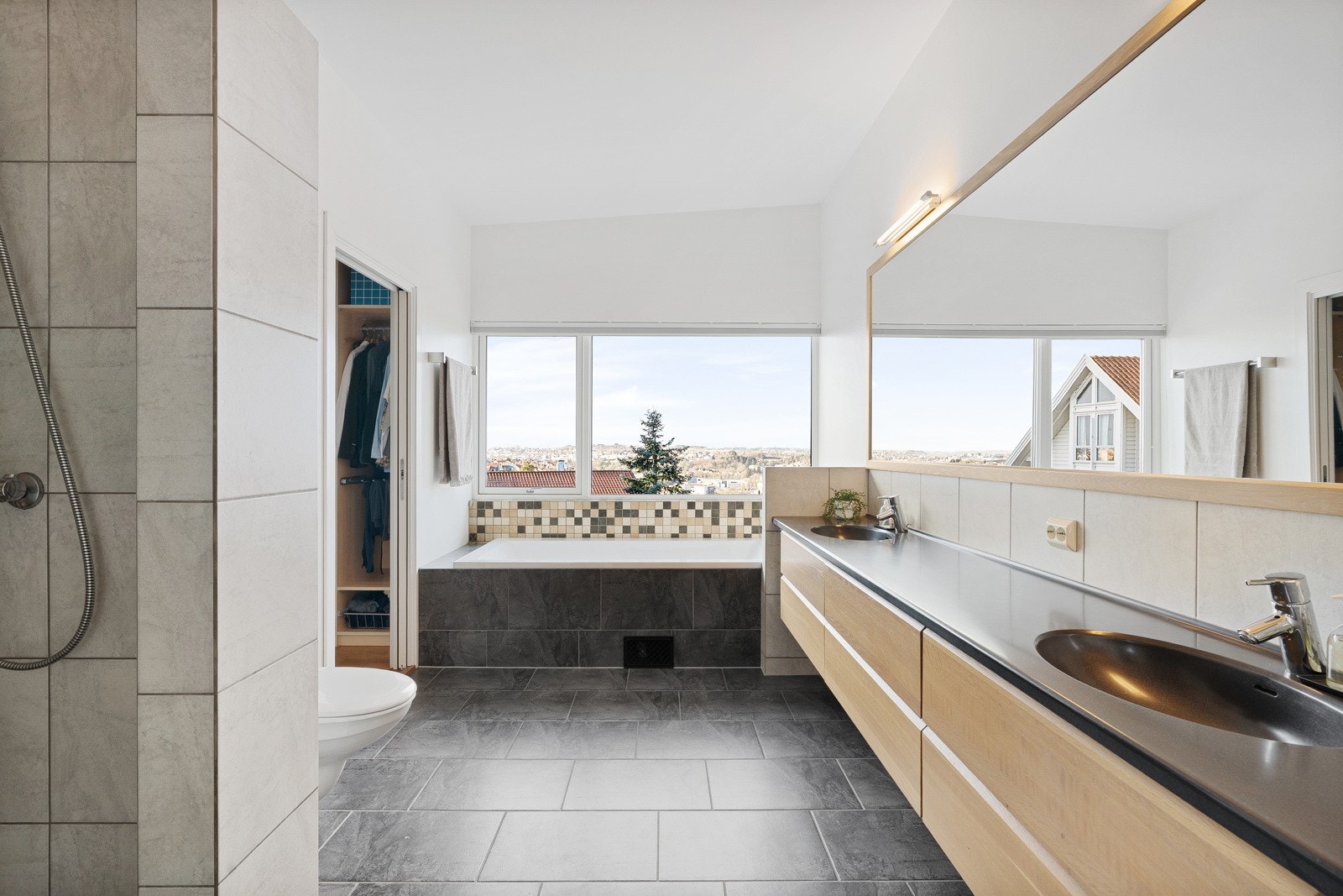 Lekkert fliselagt bad med romslig dusjhjørne, dobbel servant og badekar. Galleribilde