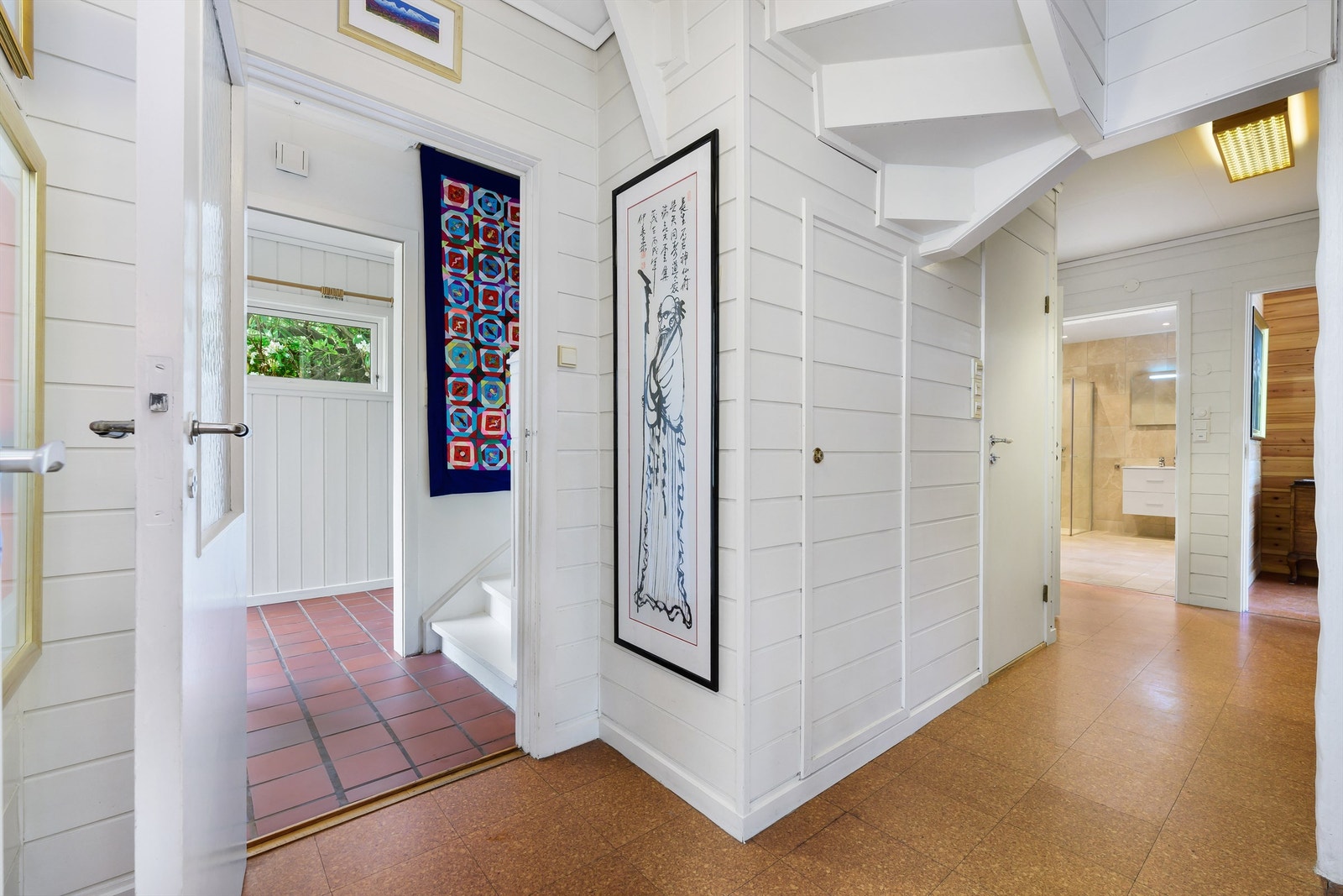 Vindfang med fliser på gulv med varmekabler og entrè med laminat. Her er det også innebygd garderobeskap under trappen. Galleribilde