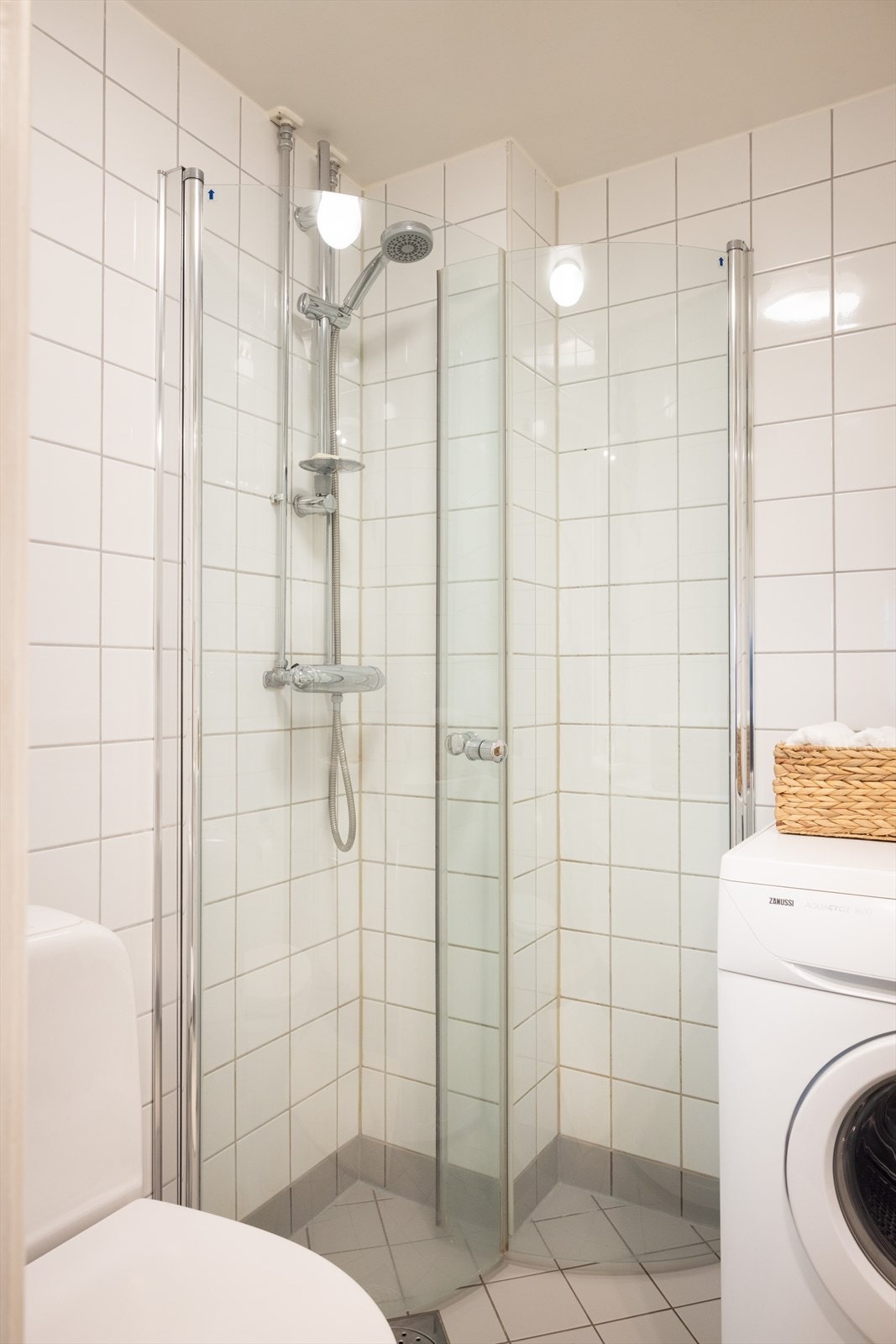 Badet er innredet med klosett, servant på innredning, speilskap med lys og dusjhjørne med svingbare glassdører. Galleribilde