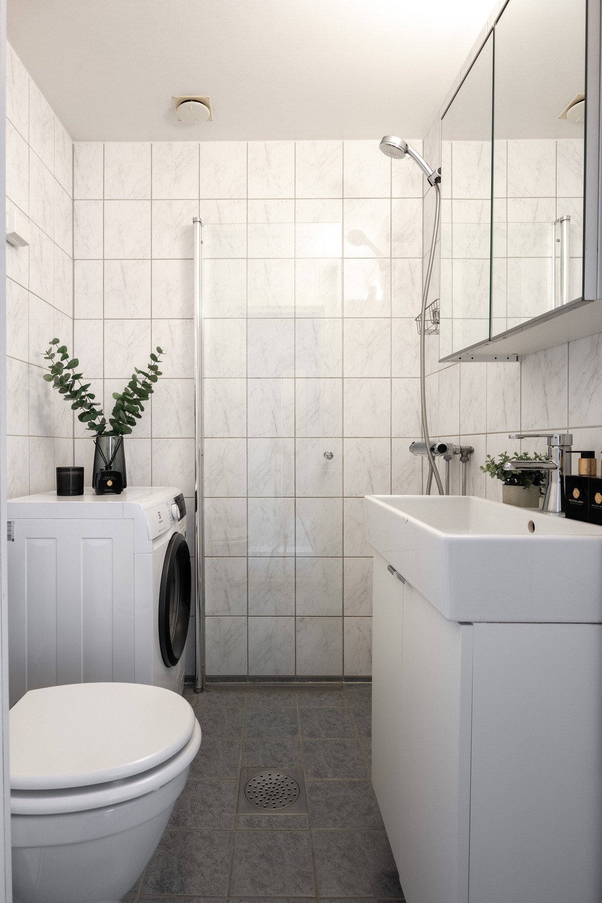 Badet er innredet med vegghengt servantskap og ovenpåliggende servant, speilskap og belysning over servant. Galleribilde