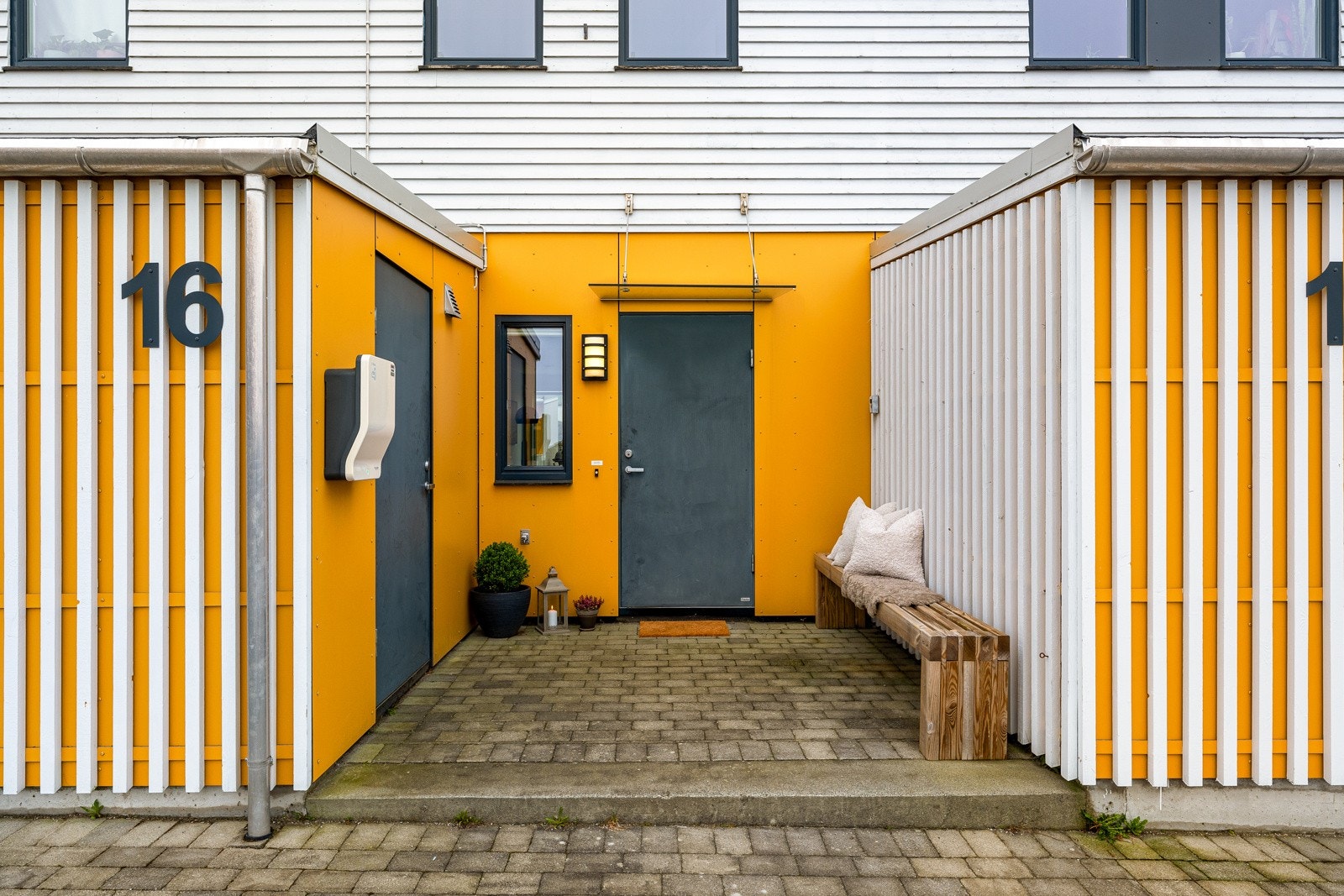 Inngangspartiet med pent steinbelagt gårdsrom og sportsbod. Galleribilde