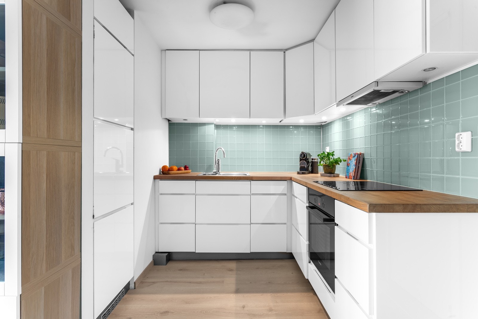 Stilren takhøy kjøkkeninnredning med heltre benkeplate og integrerte hvitevarer. Galleribilde