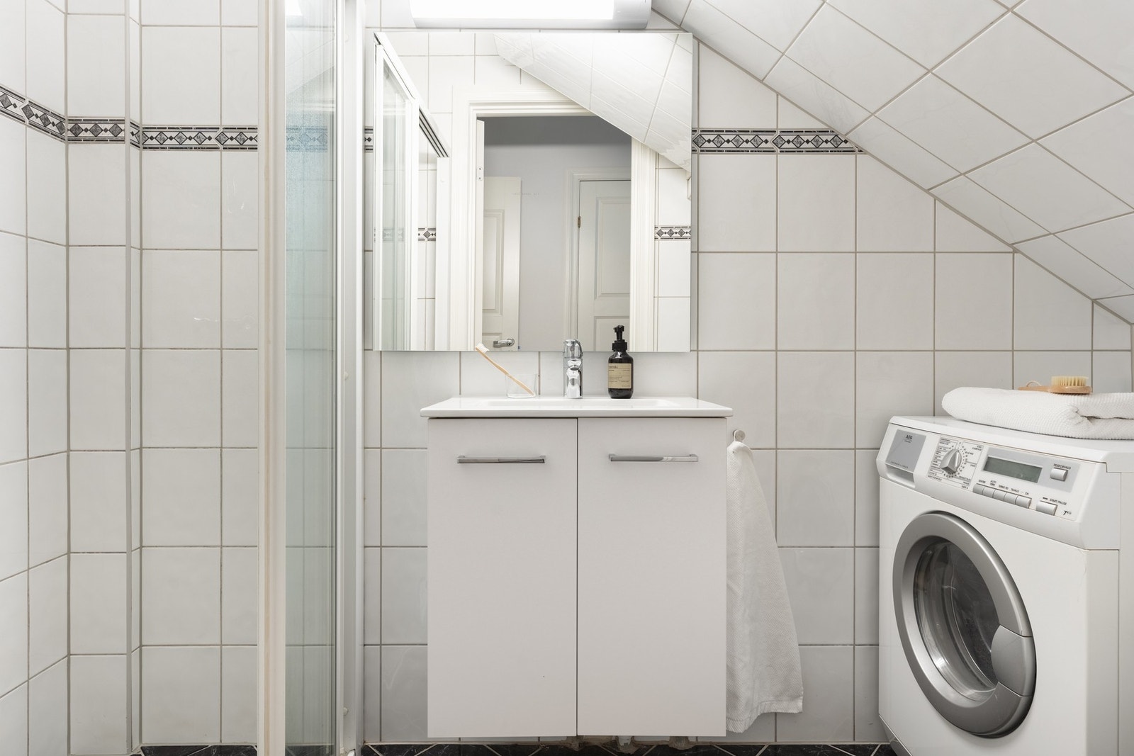 Det flotte badet er innredet med dusjhjørne, toalett, opplegg for vaskemaskin og skapinnredning med overliggende servant. Galleribilde