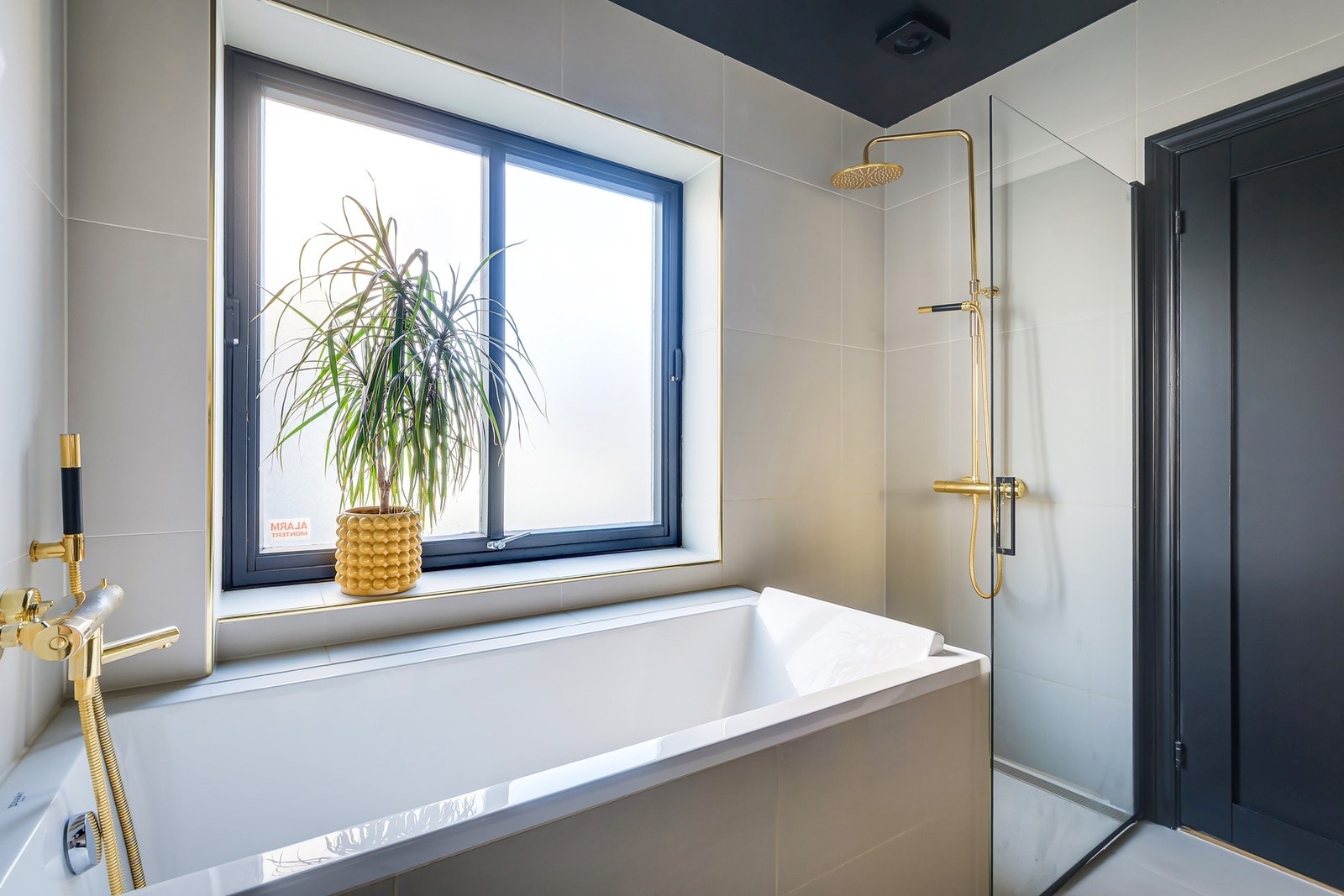 Store, lyse fliser skaper en luftig spa-følelse, mens sorte detaljer og gullarmatur gir et sofistikert preg. Galleribilde