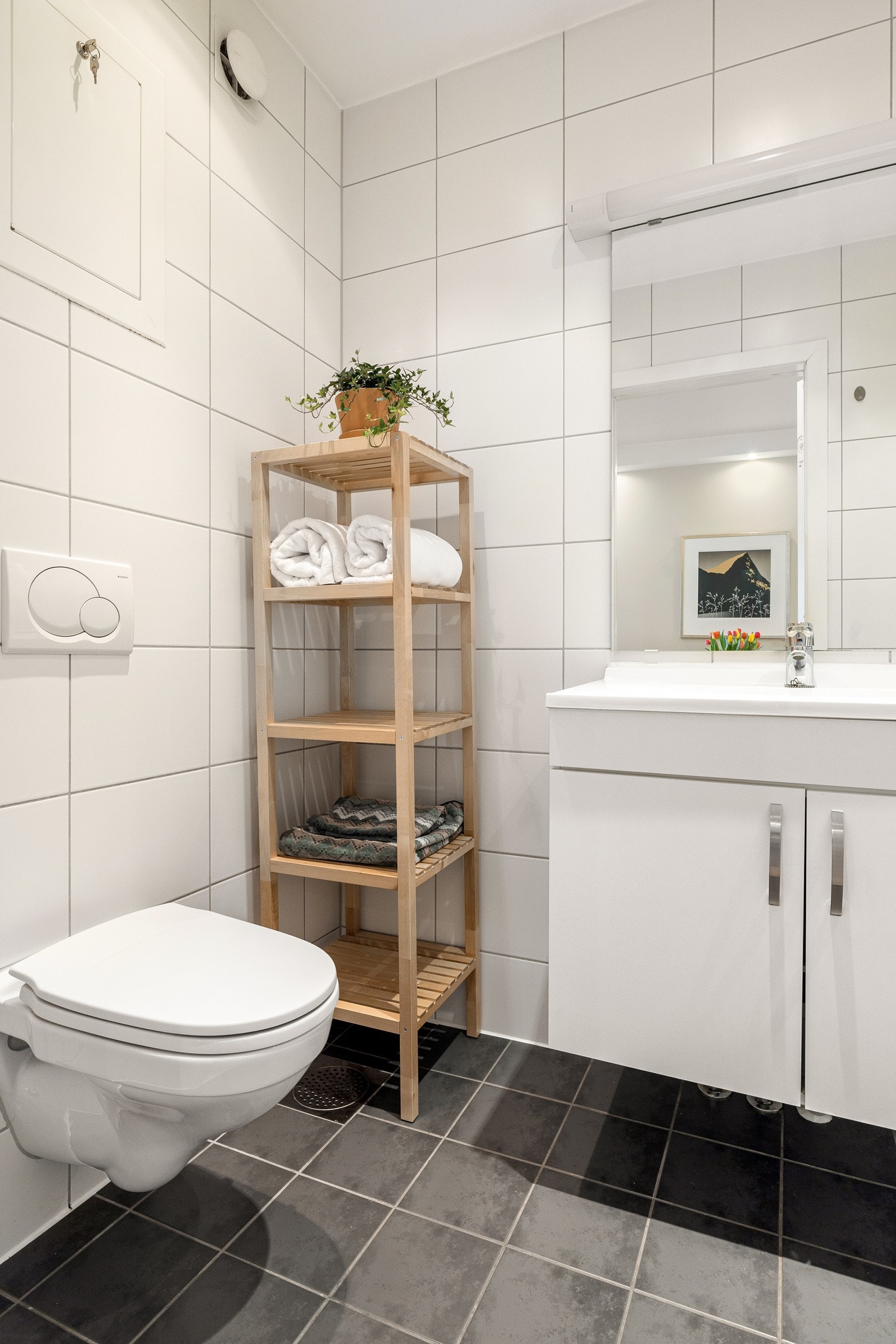 Lys baderomsinnredning med heldekkende servant, speil med belysning over. Galleribilde