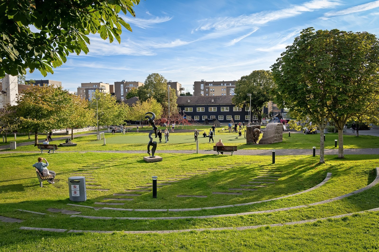 En solfylt dag i Lørenparken, hvor grønne plener og moderne skulpturer skaper en fredelig oase midt i Oslo. Galleribilde